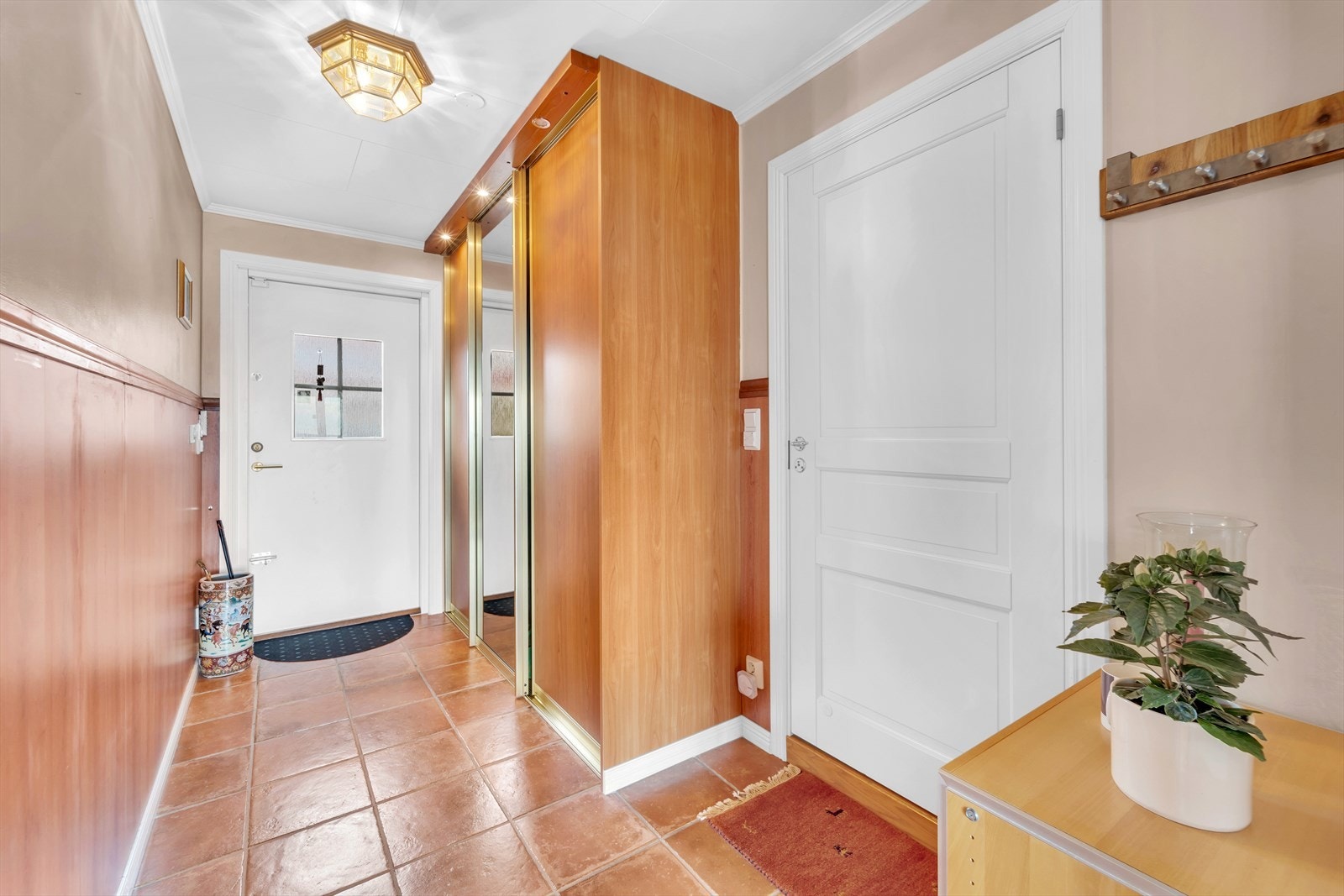 Praktisk entré med fliser på gulv og skyvedørsgarderobe til yttertøy. Galleribilde