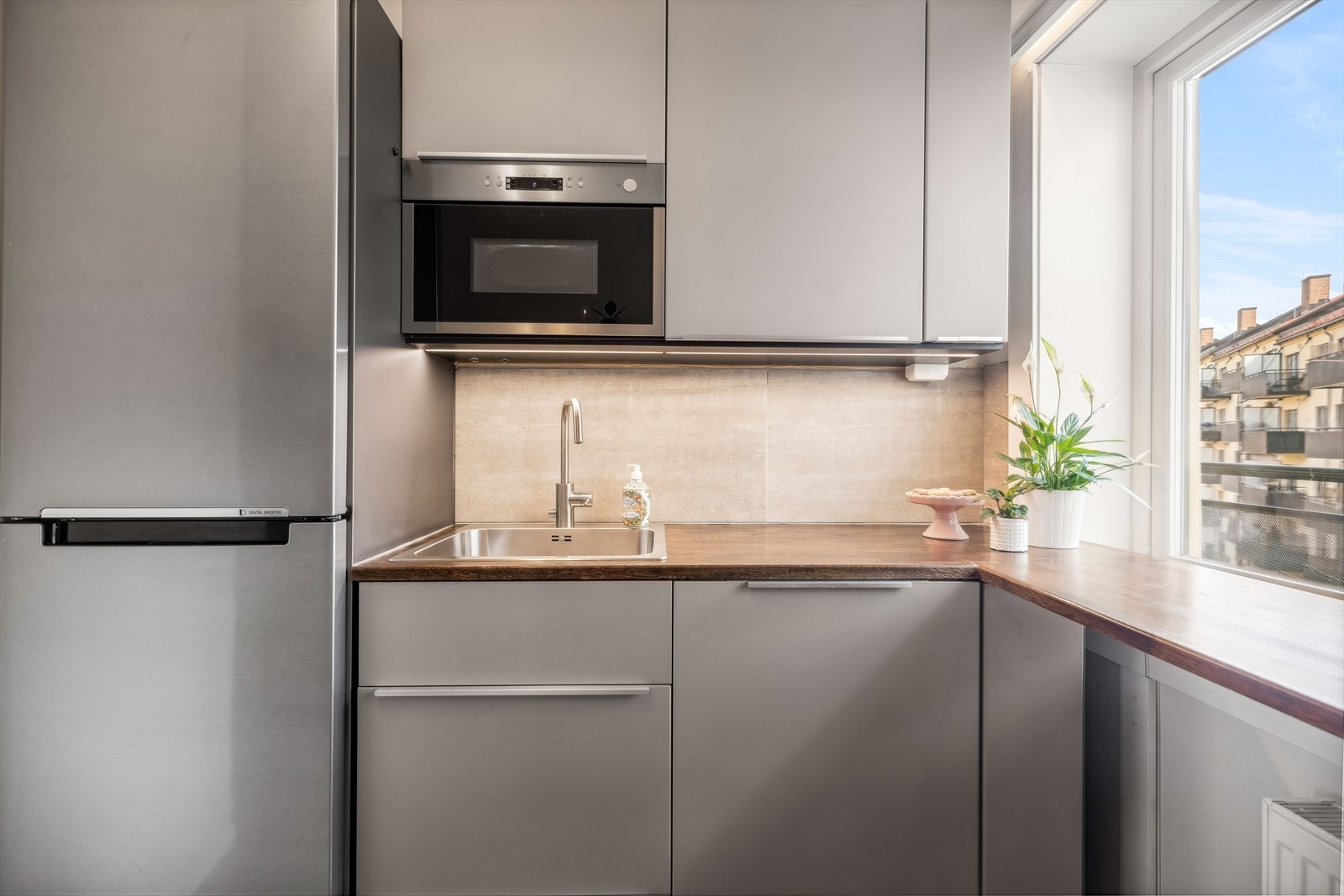 Kjøkkeninnredning med slette lakkerte fronter, beiset heltre eik benkeplate m/fliser over, enkel oppvaskkum, kjøkkenventilator i stål antatt m/kullfilter, integrert koketopp, stekeovn og mikro, samt frittstående kjøl-/fryseskap. Galleribilde