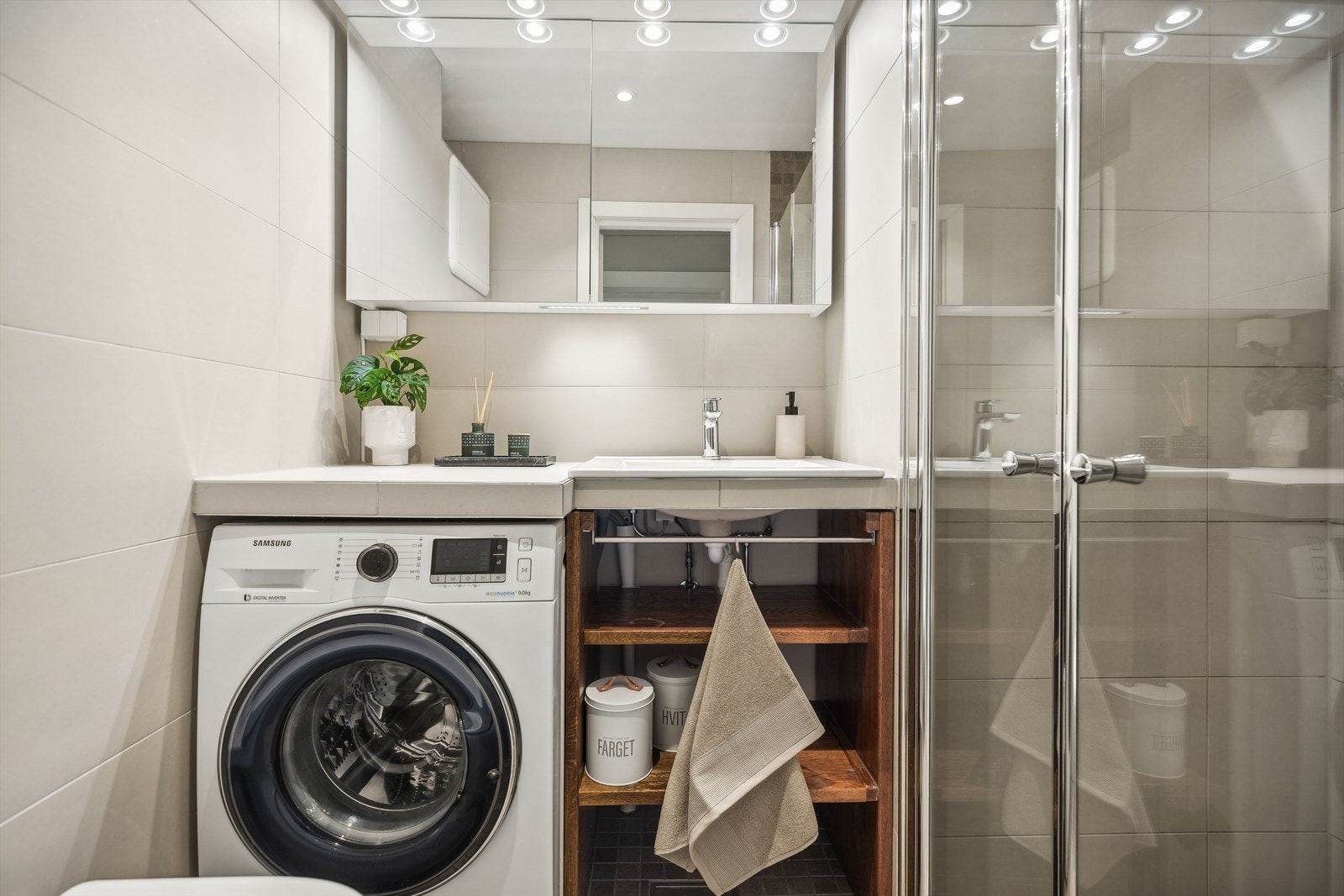 Badet har varmekabler og fliser, og består av vegghengt wc, servant, overskap m/speilfronter og overlys, inn-/utadslående dusjdører og opplegg for vaskemaskin. Galleribilde