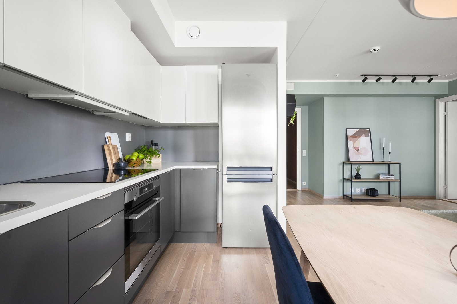 Benkeplater av laminat med nedfelt oppvaskkum med ett-greps armatur og belysning under overskap med stikkontakter på vegg. Hvitevarene er integrerte med stekeovn, platetopp og oppvaskmaskin. Kjøkkenventilator i overskap tilknyttet avtrekkskanal. Galleribilde