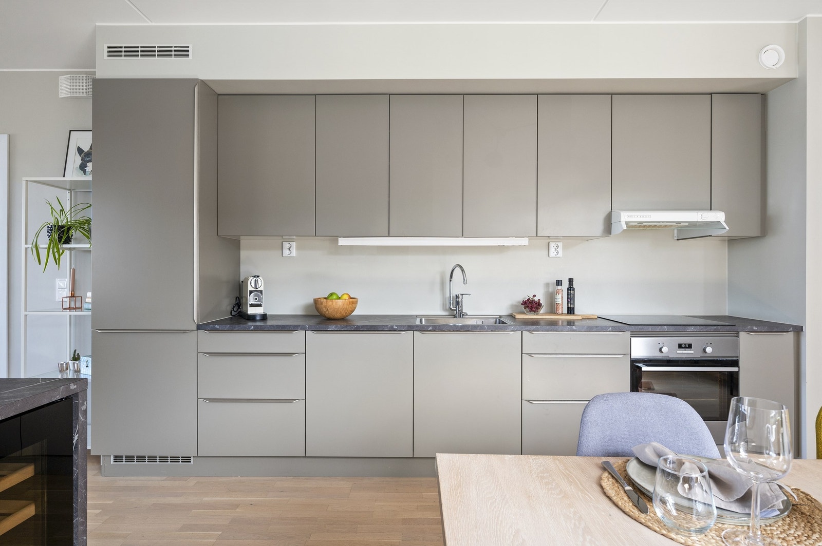 Kjøkkeninnredningen er moderne og elegant med glatte skapfronter og benkeplate av laminat samt nedfelt oppvaskkum og ett-greps armatur. Galleribilde