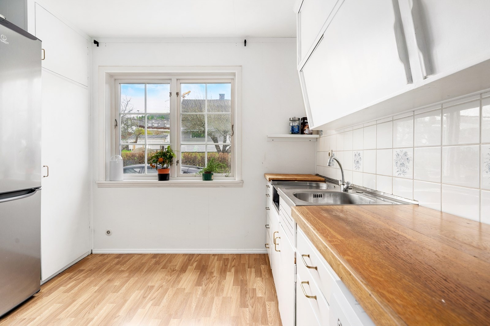 Kjøkkeninnredning med glatte, malte fronter. Tak-høye overskap. Galleribilde