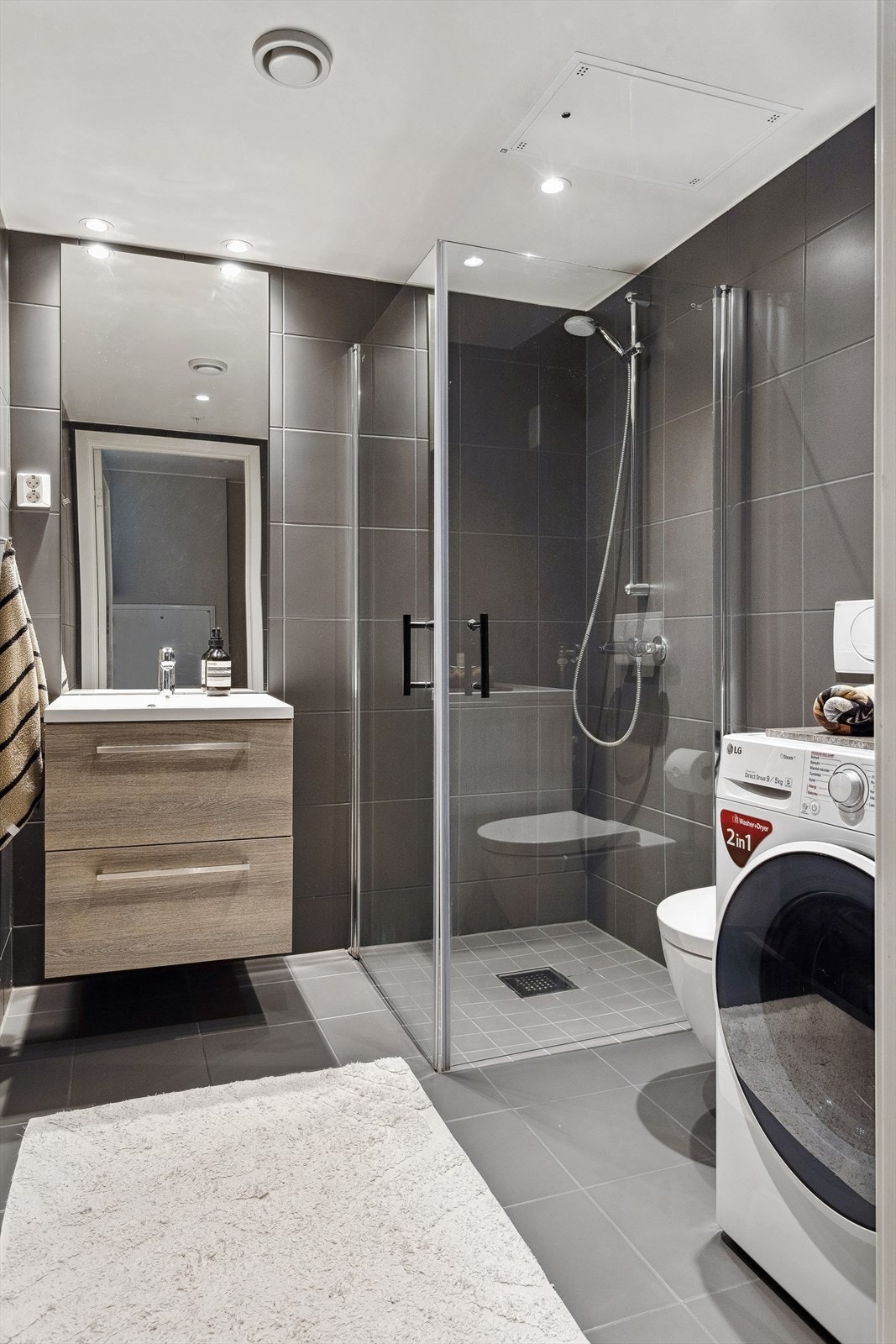 Badet består av vegghengt wc, servant med underskap, speil med overlys, inn-/utadslående dusjdører og opplegg for vaskemaskin Galleribilde