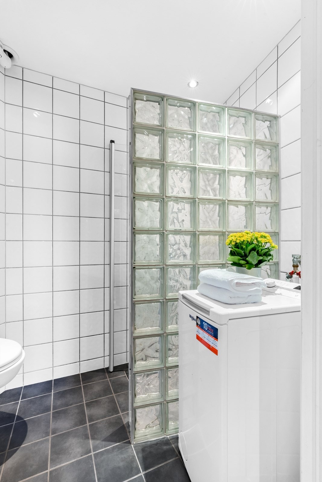 Innredningen består av servant med underskap, vegghengt toalett og dusjhjørne med glassbyggerstein. Galleribilde
