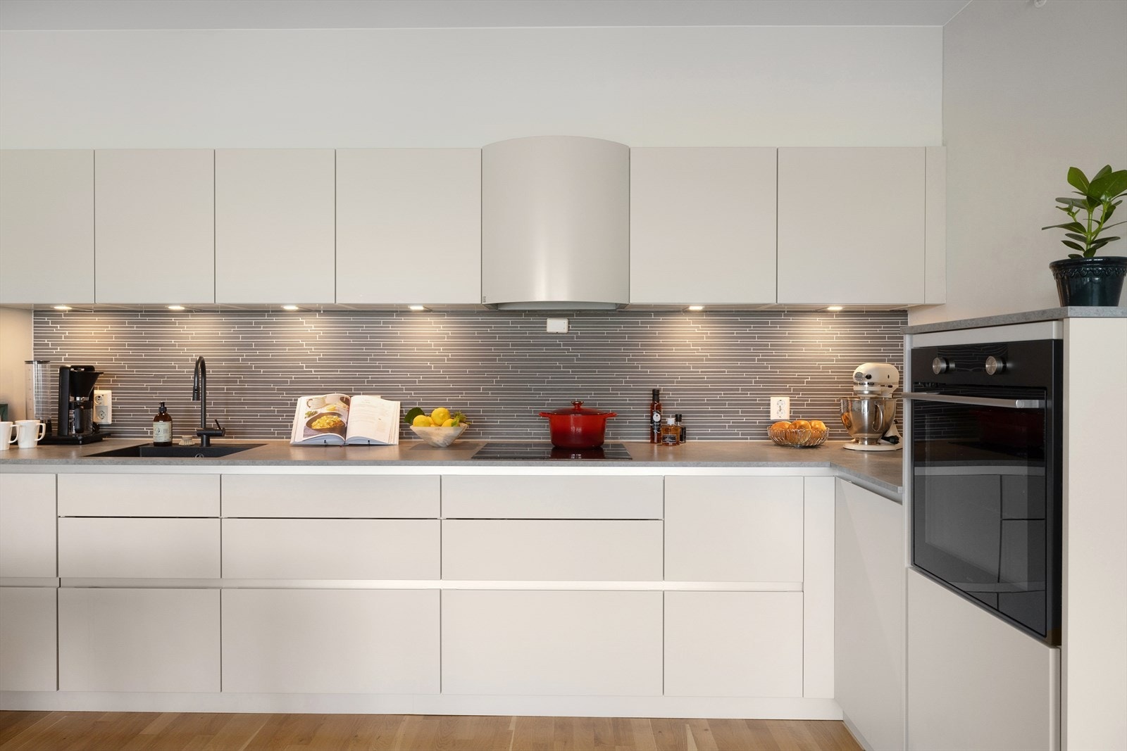 Innredning med matte fronter, benkeplater i laminat, underlimt oppvaskkum, ventilator og integrerte hvitevarer. Galleribilde