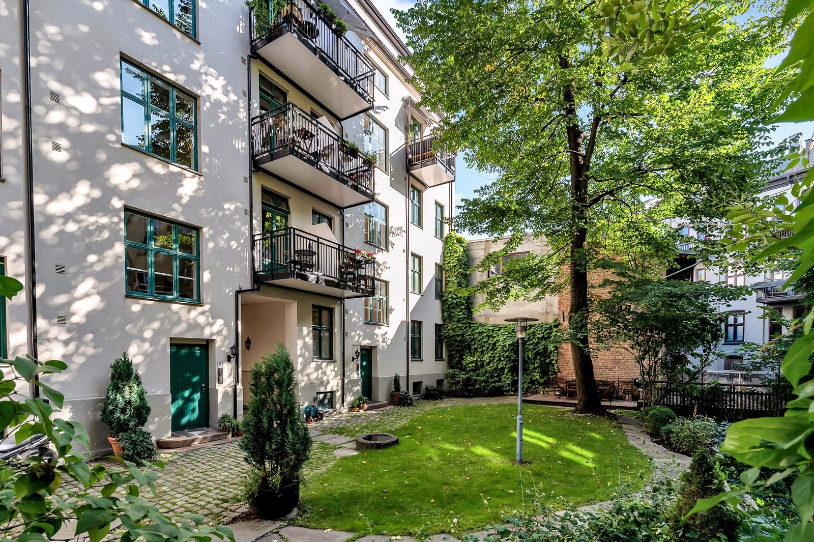 Bygården har en nydelig grønn oase av en bakgård, som er pent opparbeidet med plen, beplantninger og hellelagte internveier. Balkongen vender ut mot indre gårdsrom Galleribilde
