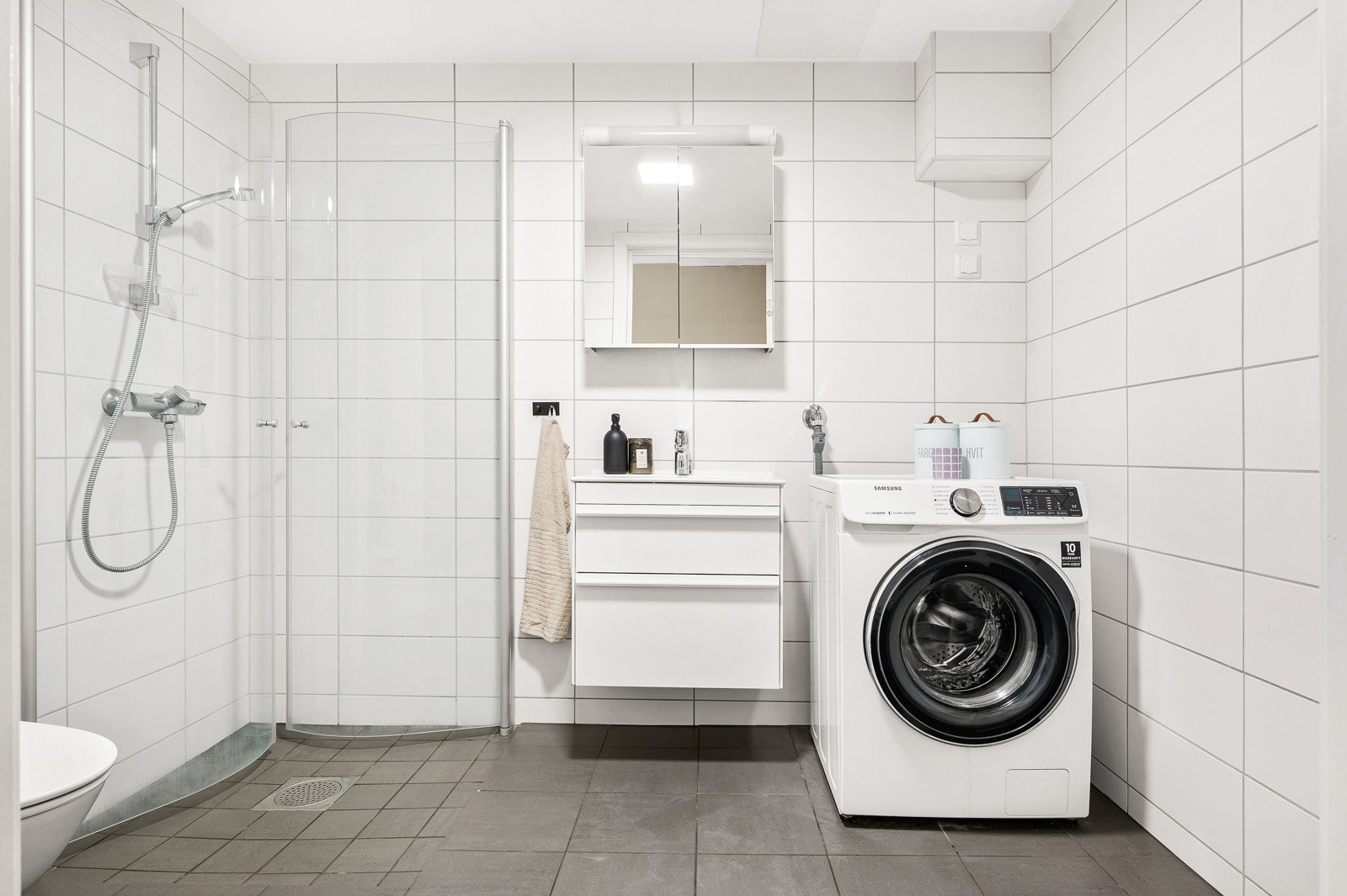 Pent og tidløst flislagt baderom fra 2020 med gulvvarme. Badet er innredet med et vegghengt toalett, dujshjørne og vegghengt servantskap, samt speilskap. Galleribilde