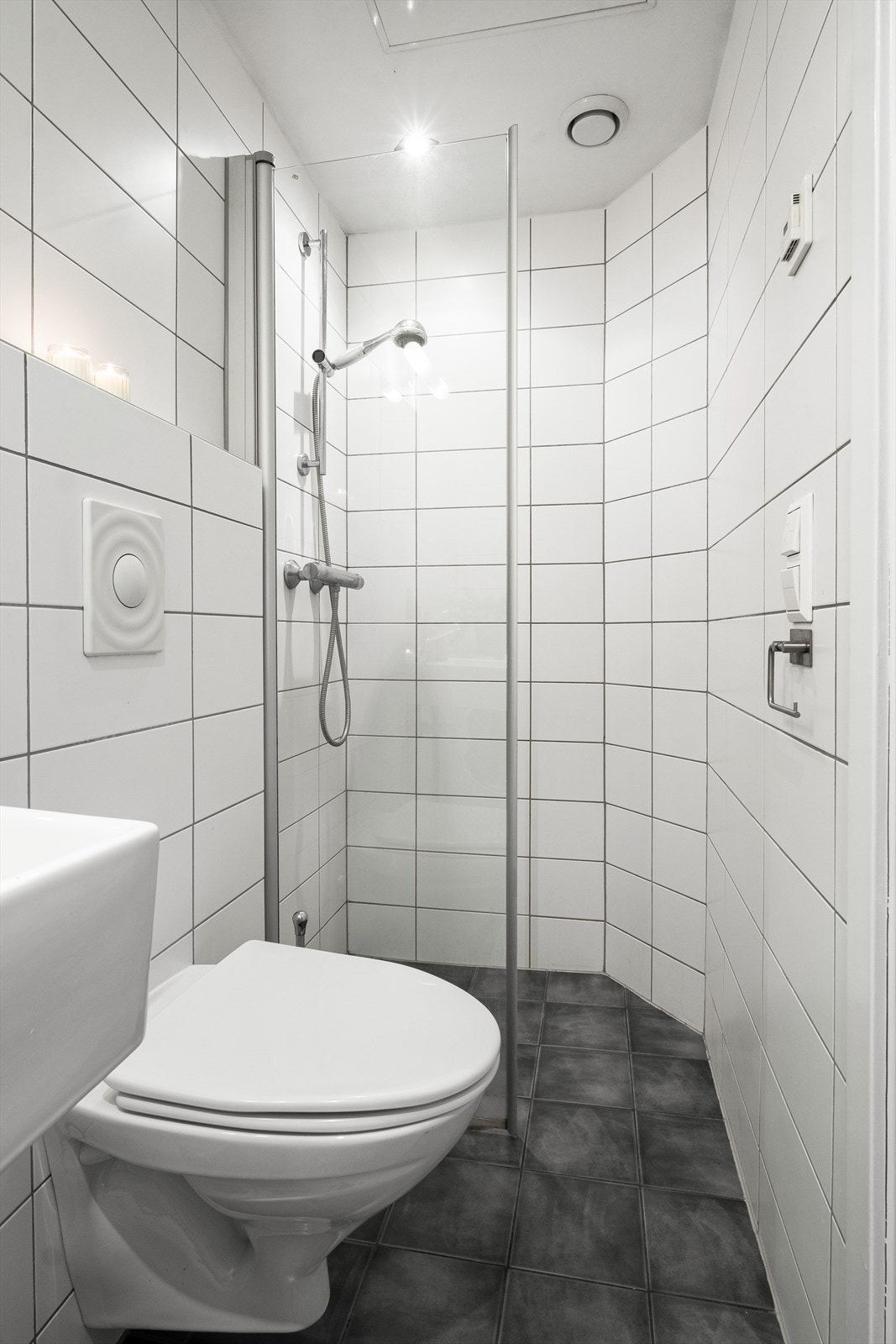 Badet er innredet med vegghengt toalett, dusjhjørne, servant samt speil med lys i rommet. Galleribilde