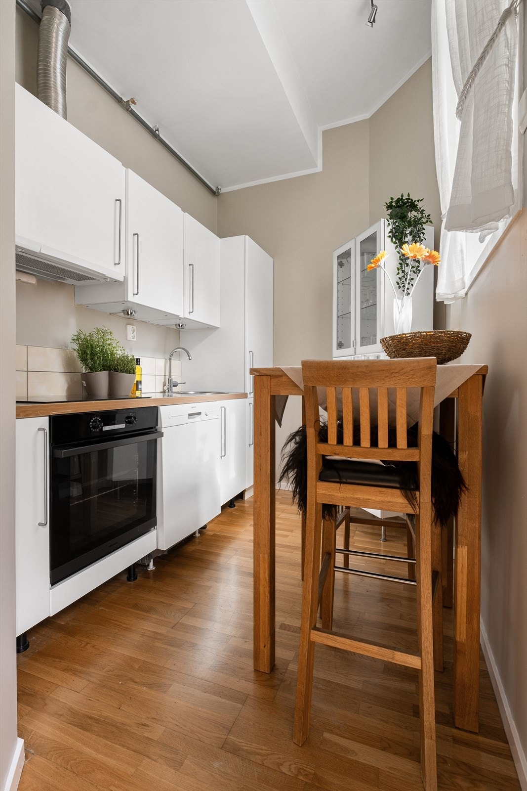 Innbydende og praktisk kjøkken med laminert benkeplate, slette skapfronter, flislagt backsplash og ventilator med utkast til friluft. Galleribilde