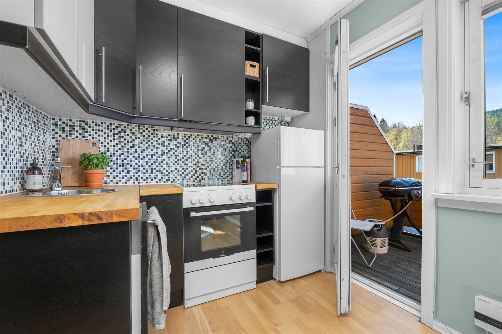 Kjøkkenets hjørneplassering gir et naturlig skille mellom stue og kjøkken. Galleribilde