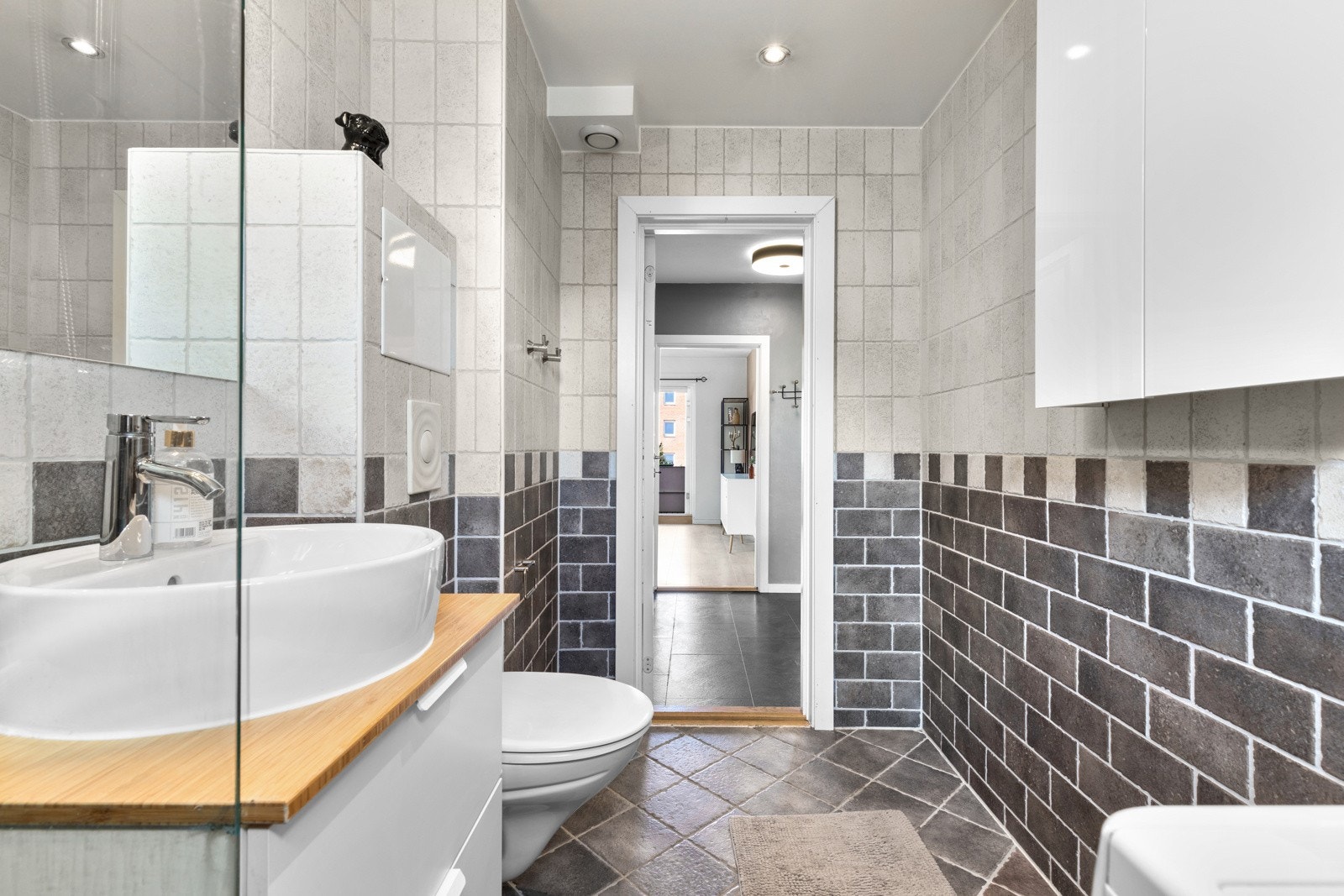 Her er det lyse- og mørkegrå fliser på veggene, downlights i himlingen og mørkegrå fliser på gulv med vannbåren gulvvarme. Galleribilde