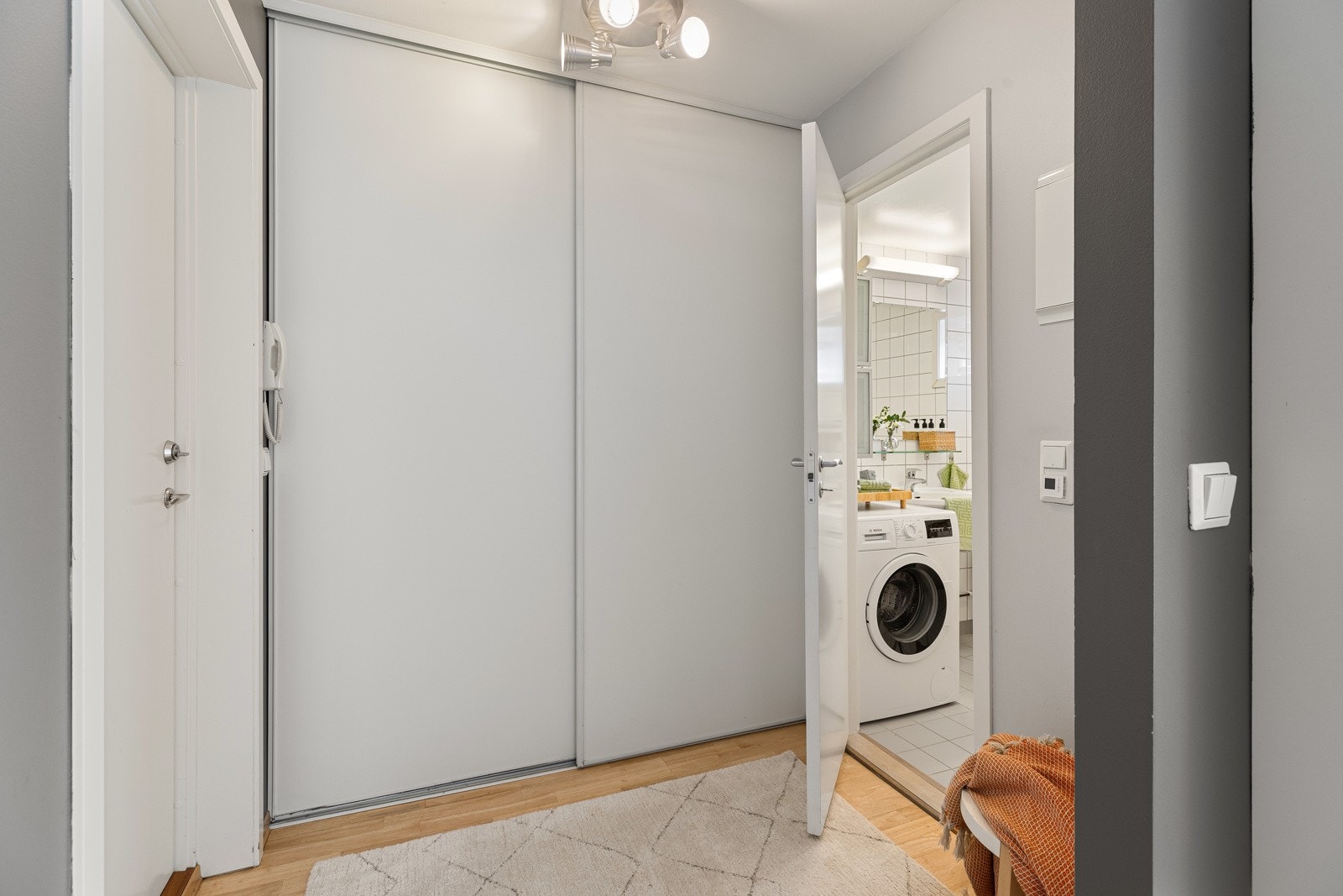 Romslig skyvedørsgarderobe med profilerte hvite fronter i entréen. Galleribilde