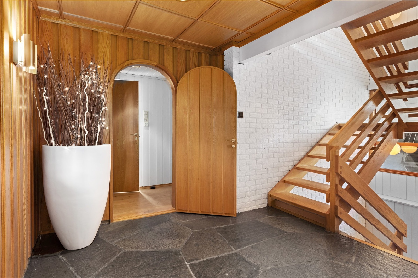 Entré med skiferstein på gulv, gulvvarme, malt overflate og panel på vegger. Trevirke i tak med downlights. Galleribilde