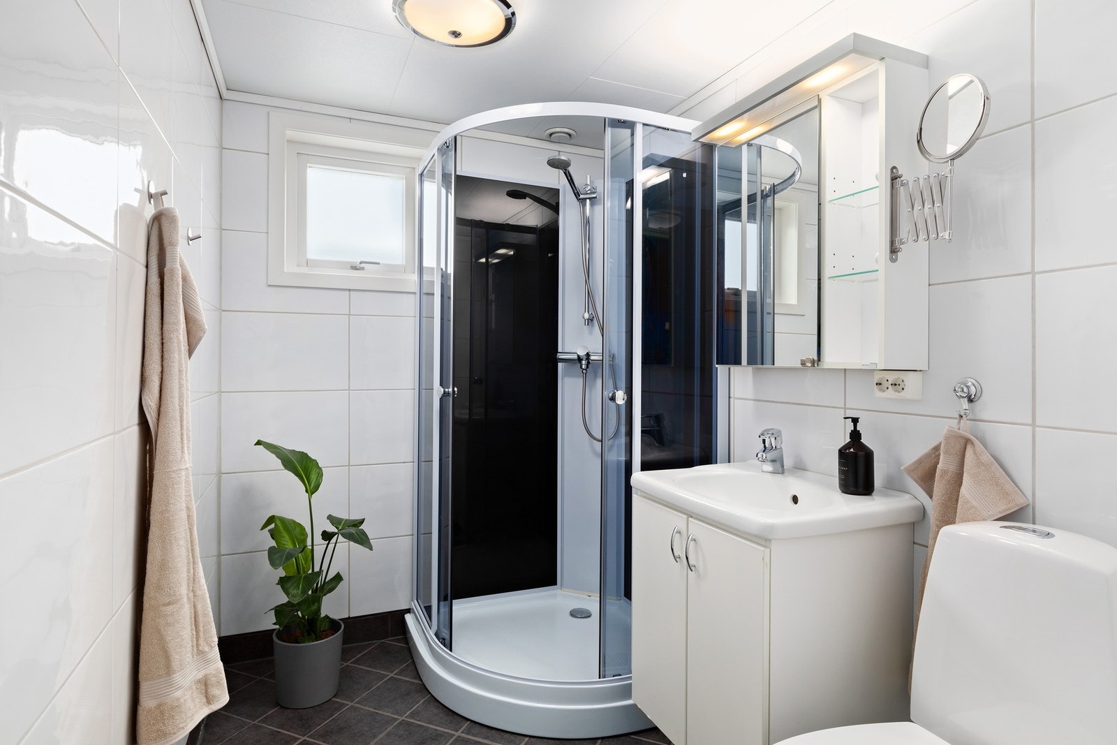 Flislagt baderom i 1. etasje med gulvvarme, dusjkabinett, wc, servant, servantskap og mekanisk avtrekk. Galleribilde