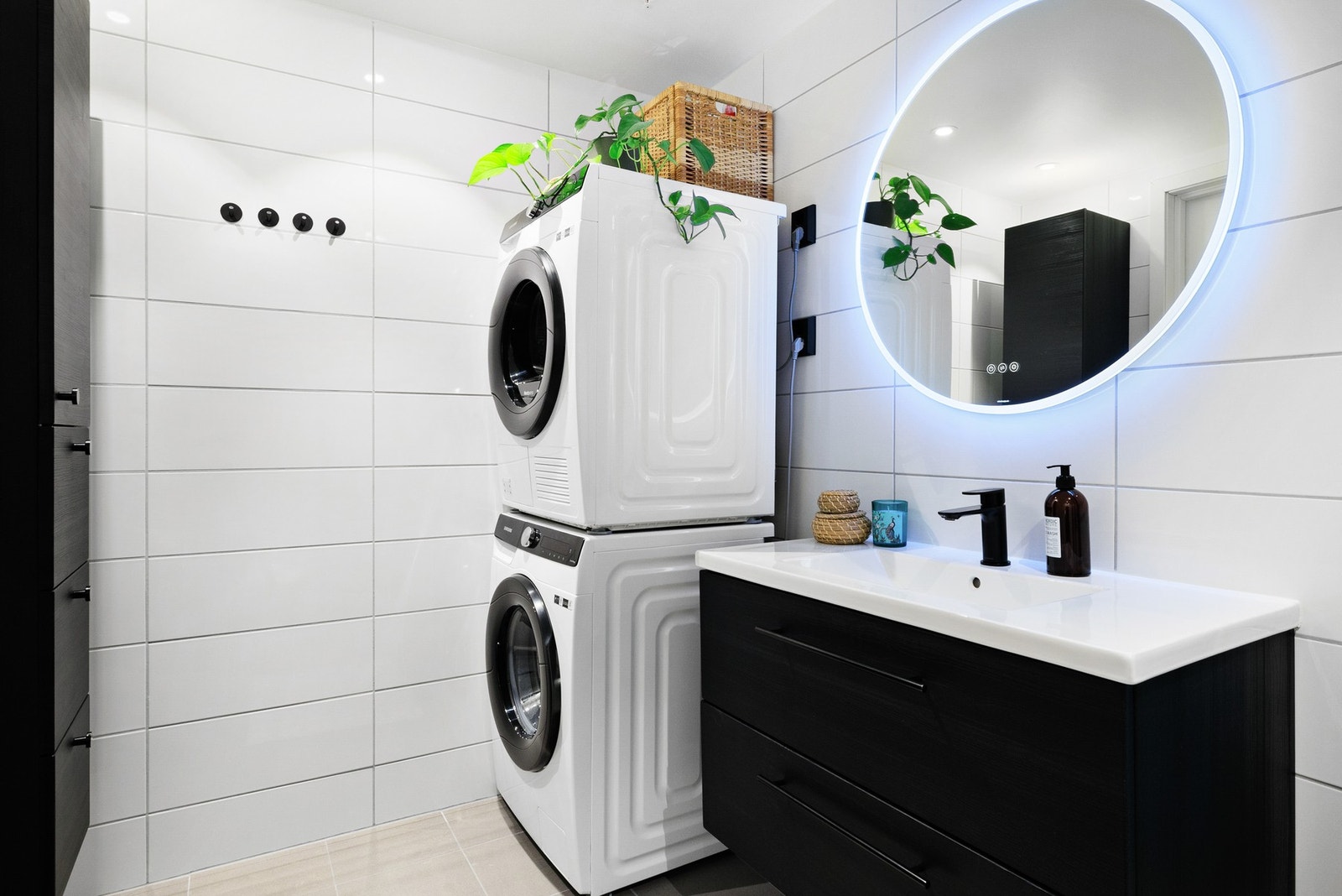 Badet er utstyrt med dusjhjørne, vegghengt toalett, baderomsinnredning og opplegg for vaskemaskin Galleribilde