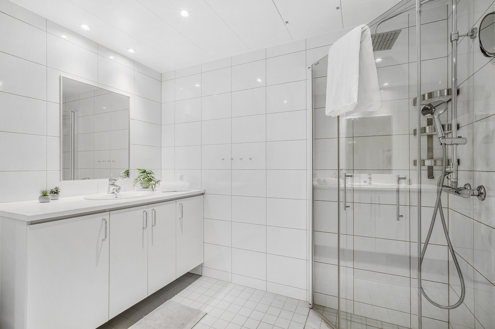 Flott flislagt bad med dusjhjørne, innredning og vegghengt WC. Galleribilde