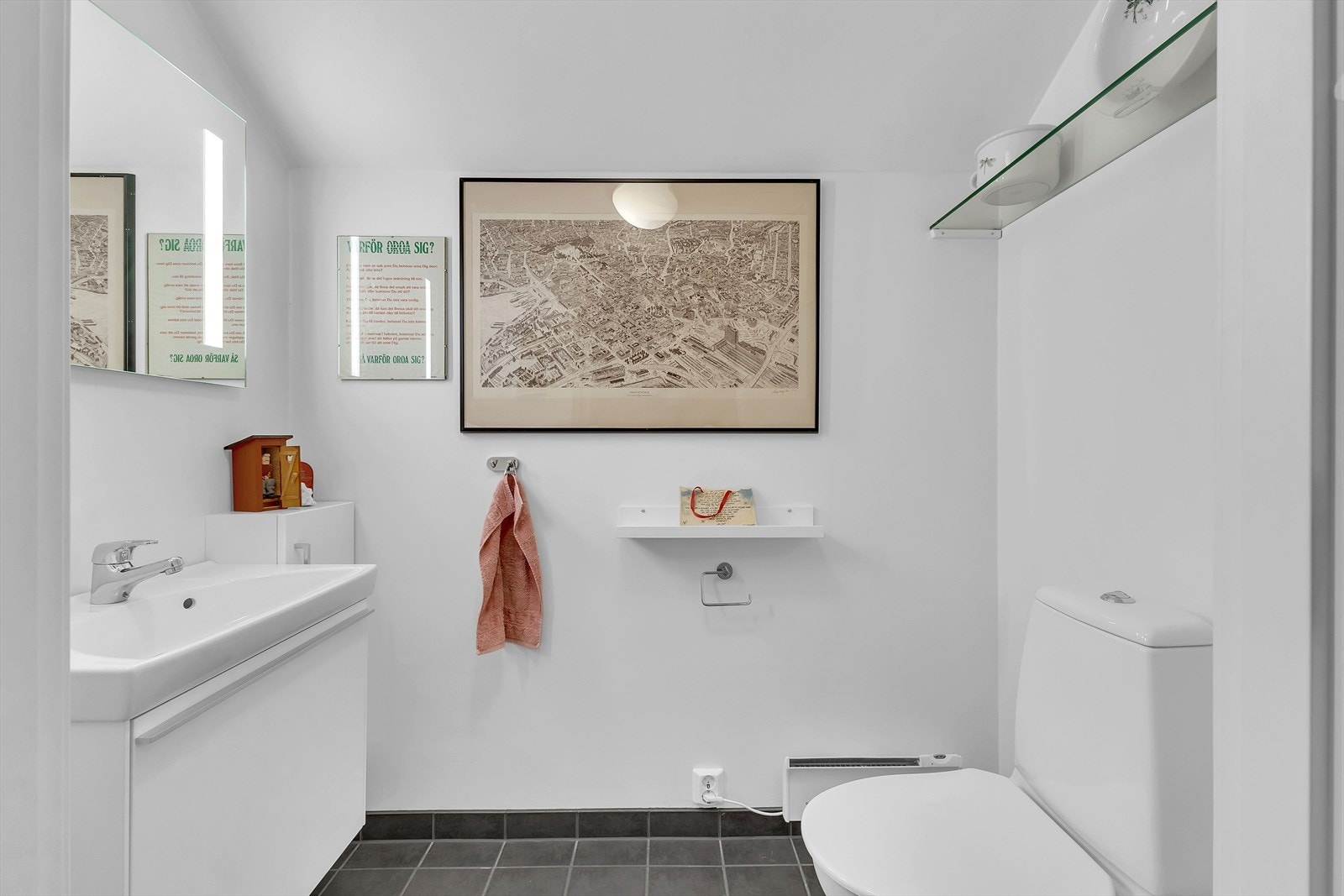 Toalettrommet har flislagt gulv og malte plater på vegger og i himling. Rommet er innredet med wc på sokkel, baderomsinnredning med heldekkende servant, samt speil og vegghyller. Galleribilde