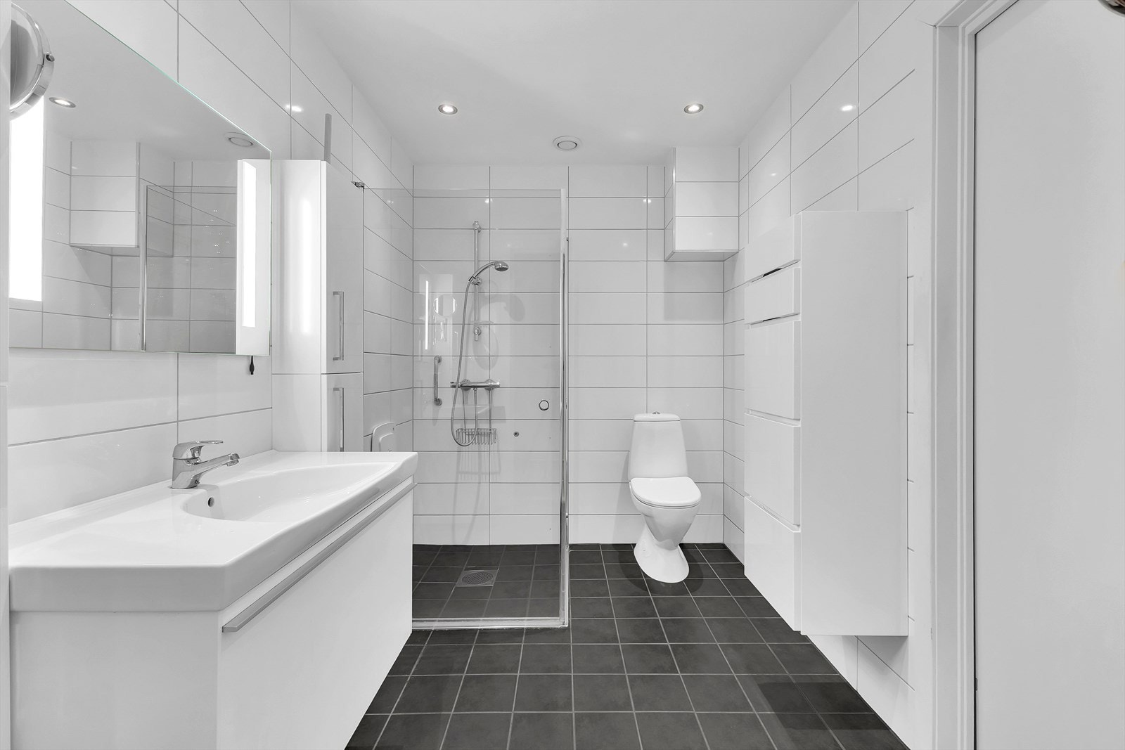 Bad/vaskerom av god størrelse. Rommet har flislagte vegger og gulv. Det er montert elektrisk varmekabel i gulvet. Galleribilde