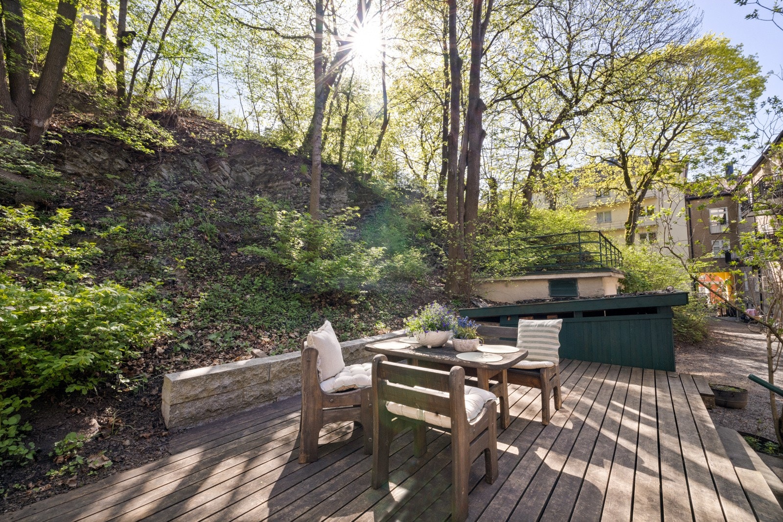 Stor innergård med beplanting, trær, platting, lekehus, huskestativ og sittegrupper for beboere Galleribilde