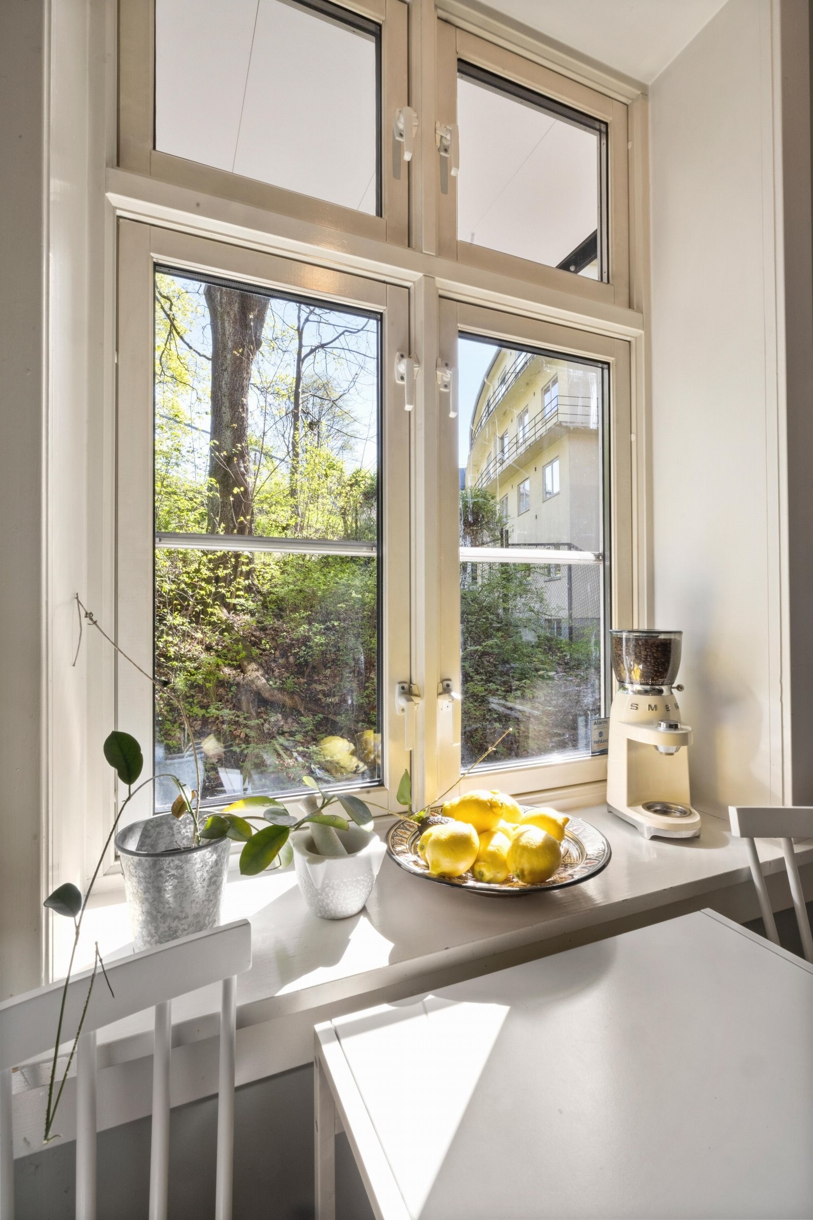 Det er plass til kjøkkenbord foran vinduspost som vender ut mot rolig bakgård Galleribilde