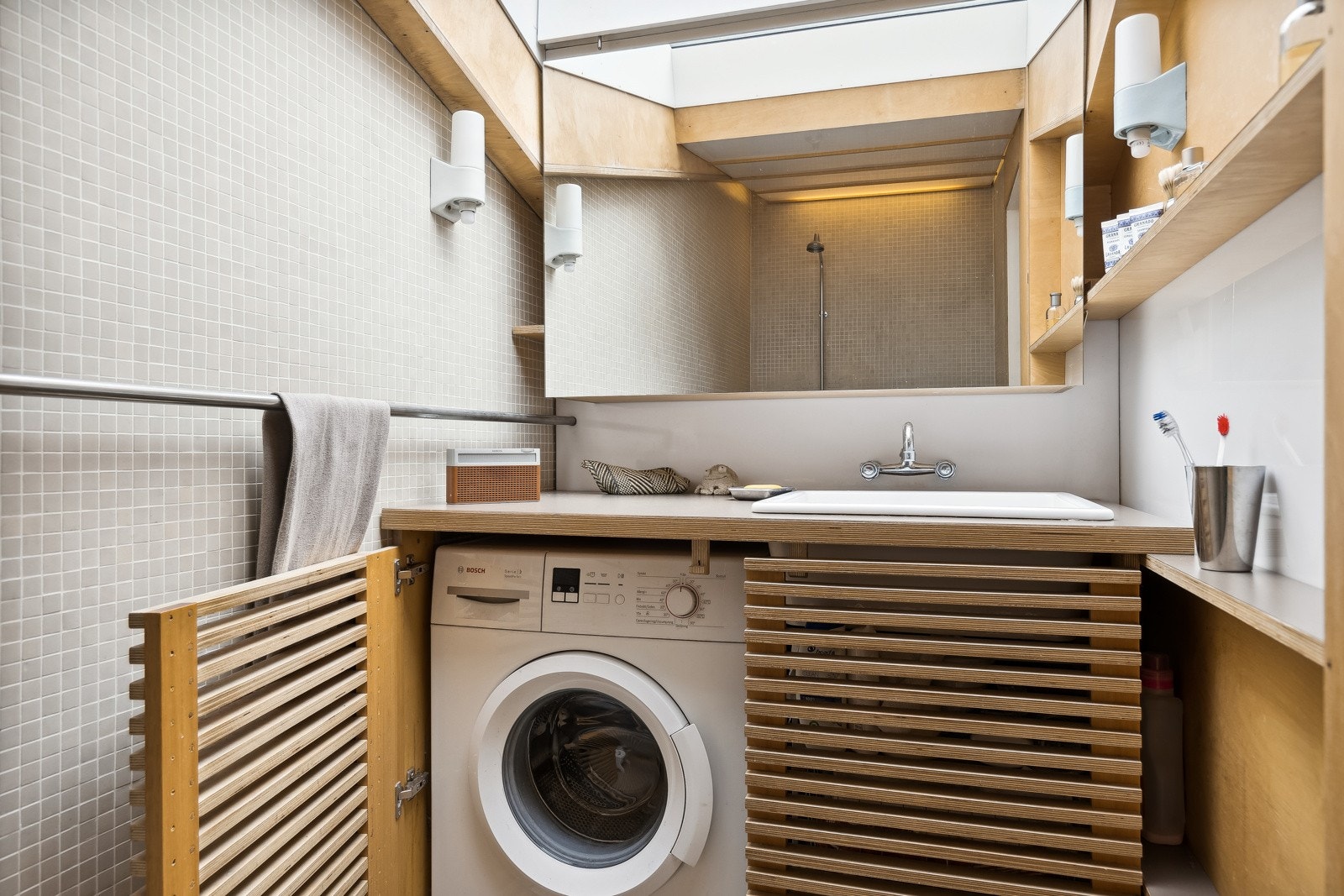 Baderomsinnredningen er godt utnyttet og inneholder servantskap, hylleløsning og speil. Opplegg for vaskemaskin. Galleribilde