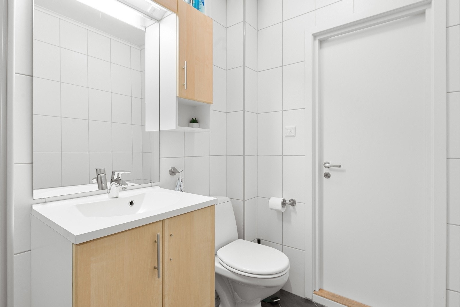 Badet er utstyrt med servanten med speil og veggskap, frittstående toalett og dusjhjørne. Det er montert fuktstyrt avtrekksvifte i himling og lufteventil på yttervegg. Varmekabler i gulv. Galleribilde