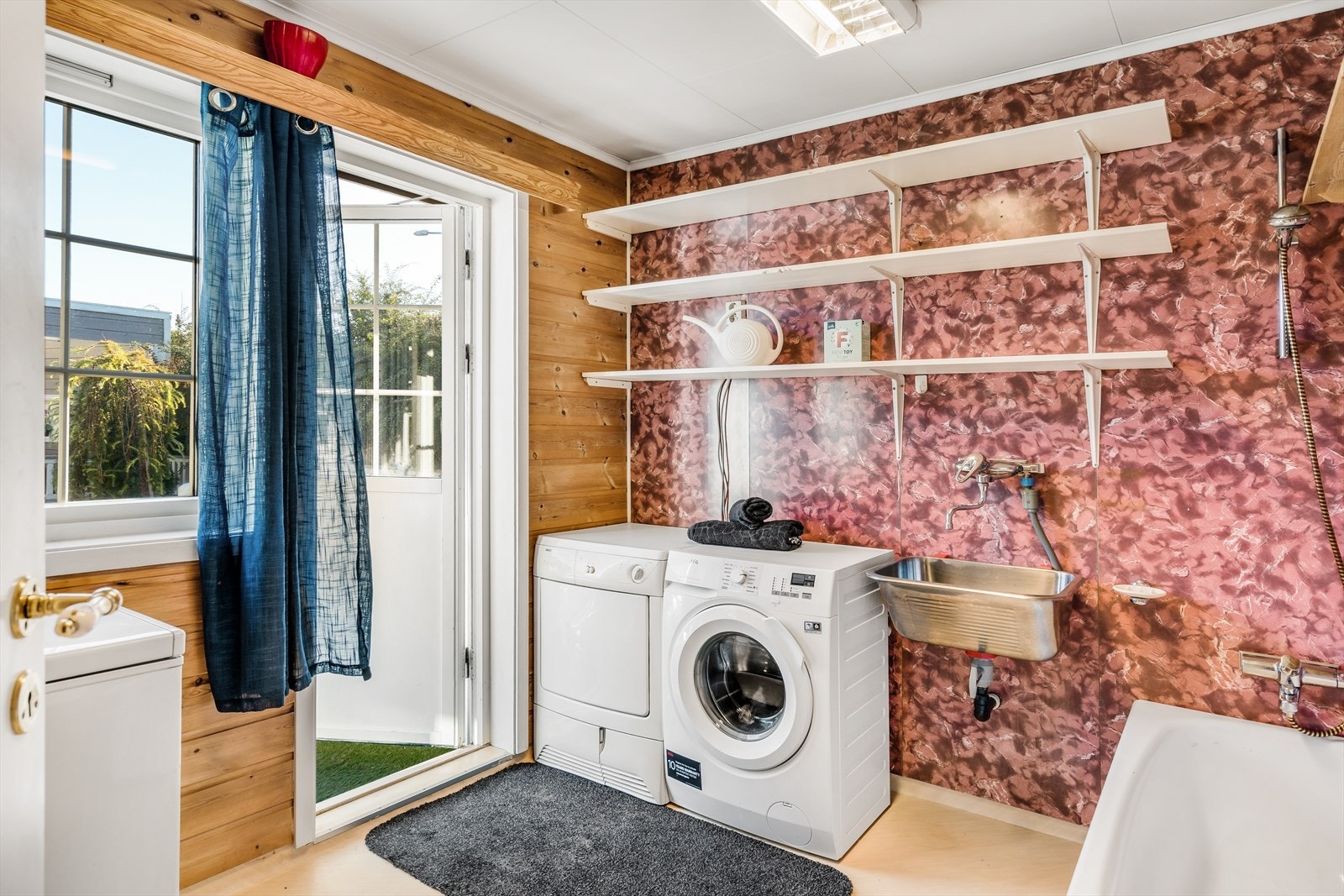 Vaskerommet fra byggeår har gulvbelegg med varmekabler, våtromsplater og trepanel, samt hvite himlingsplater. Det er montert badekar, skyllekum på vegg, opplegg for vaskemaskin og diverse hyller. Galleribilde
