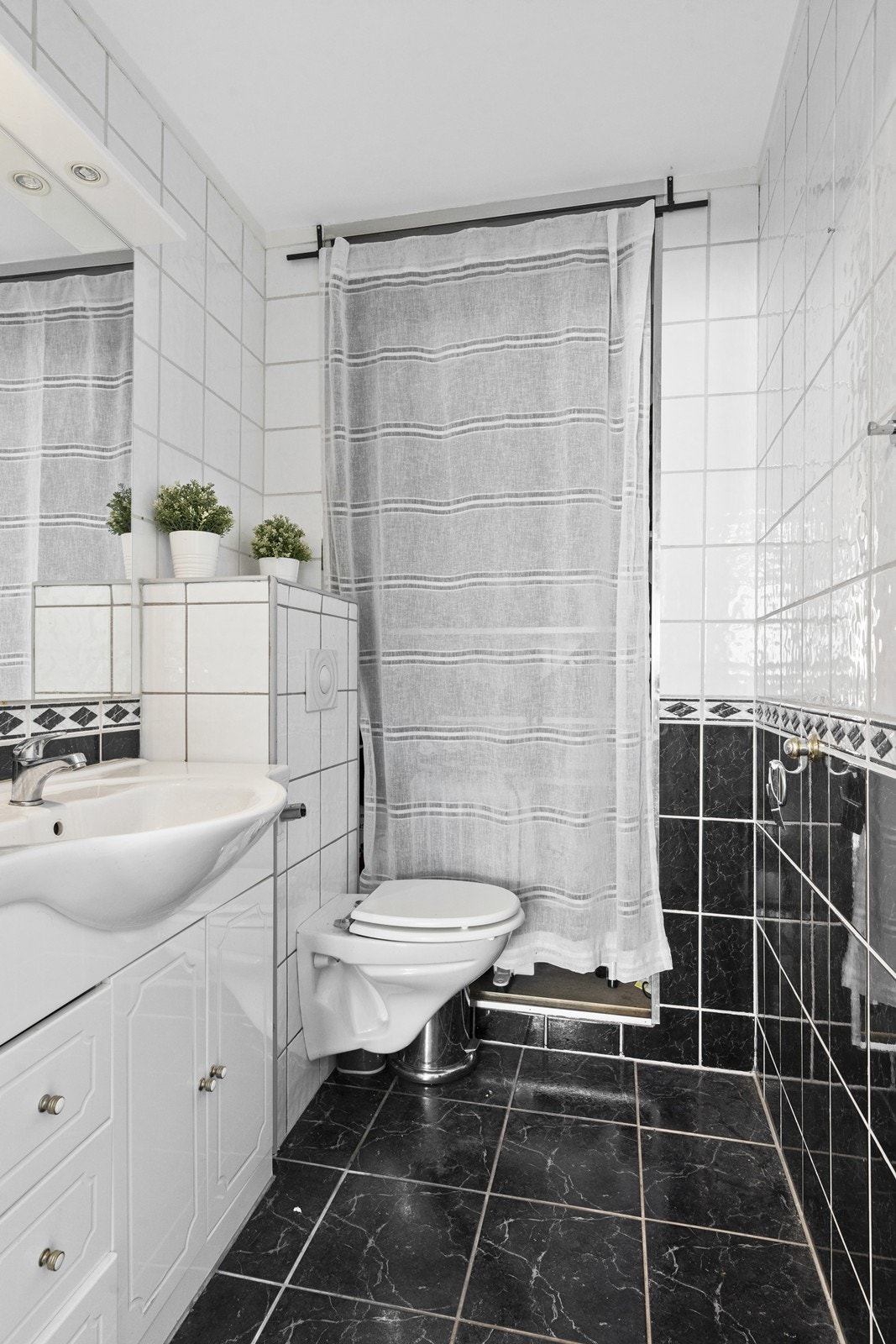Praktisk gjestetoalett med tilgang fra entréen. Overflatene er flislagte og rommet er utstyrt med vegghengt wc og servantinnredning med skuffer og underskap. Galleribilde