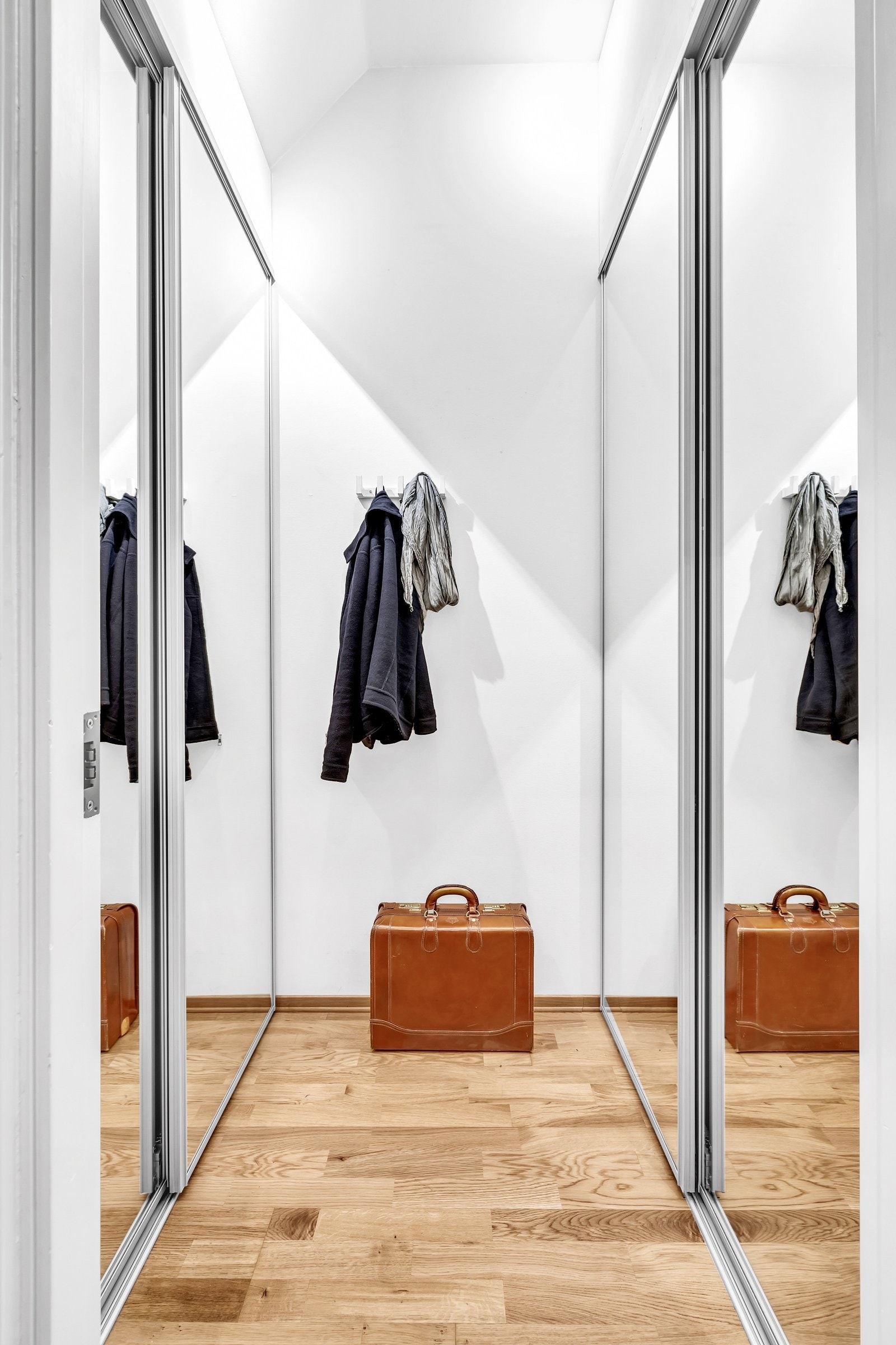 Walk-in-garderobe med to store skyvedørsgarderober, begge med speil. Galleribilde