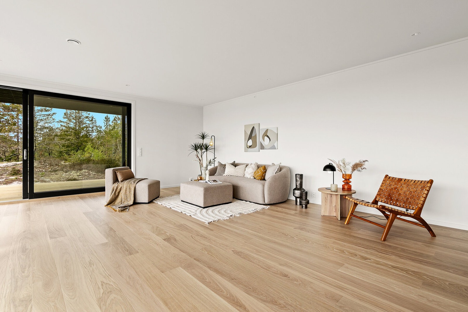 Stor stue i åpen løsning mot kjøkkenet og utgang til overbygd terrasse og terreng Galleribilde