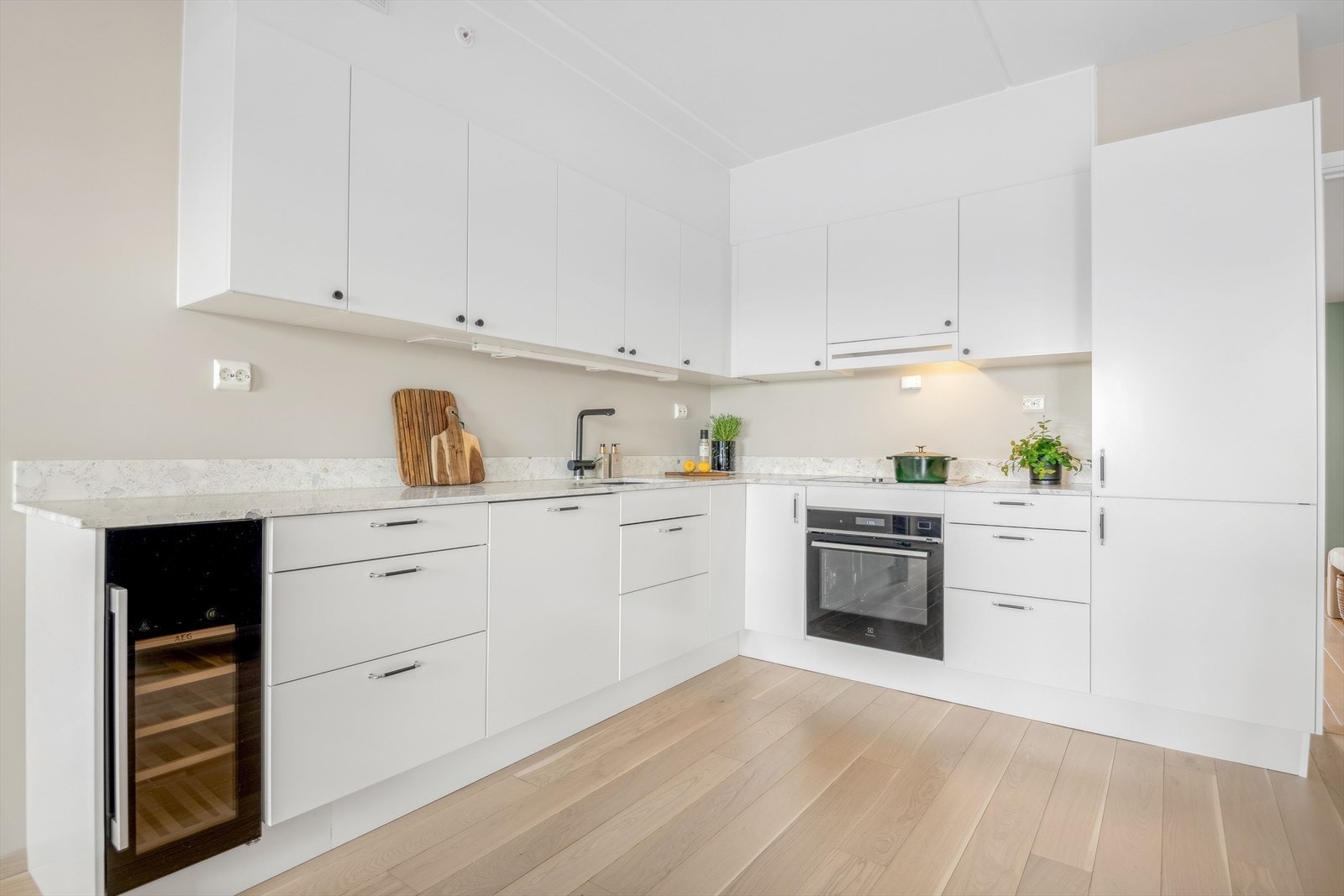 Påkostet kjøkken fra Norema. Kjøkkeninnredning med hvite glatte fronter og terrazzo benkeplate. Galleribilde