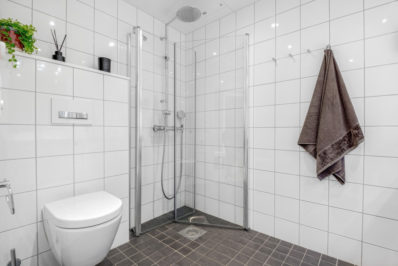 Lekkert og romslig baderom fra 2018. Romslig dusjhjørne med veggmontert dusjdør, innredning med heldekkende servant og speil, og veggmontert klosett. Galleribilde