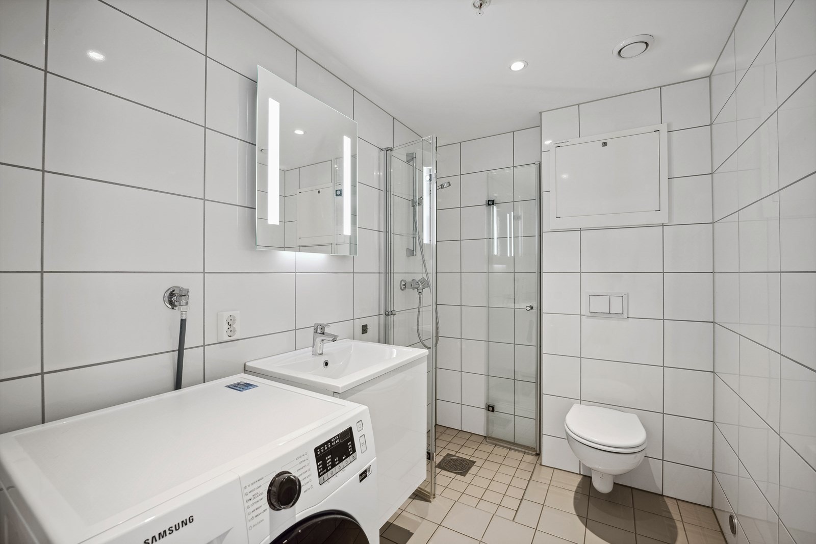 Flott fliselagt bad/wc med dusjvegger og vegghengt toalett Galleribilde