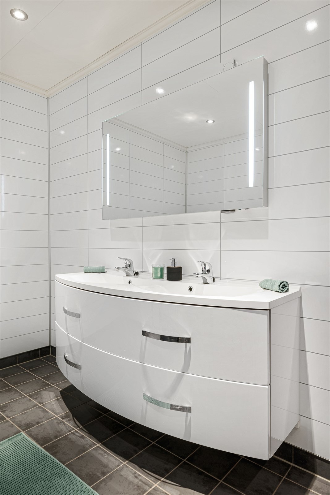 Badet er utstyrt med dusjnisje, vegghengt toalett og dobbel servantinnredning. Galleribilde