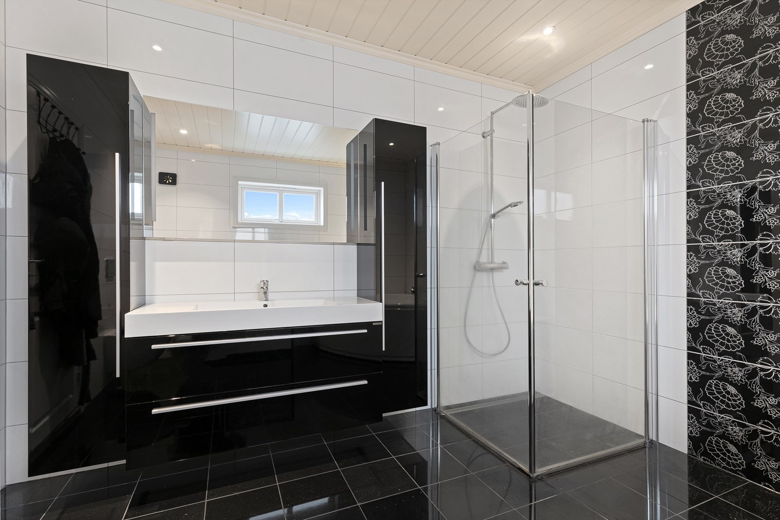 Innredningen består av hjørnebadekar med massasjefunksjon, vegghengt wc, dusjsone med fossefalldusj med plassbesparende glassdører (ut- og innadslående), samt servant i svart skuffeseksjon med speil, belysning og høyskap. Galleribilde