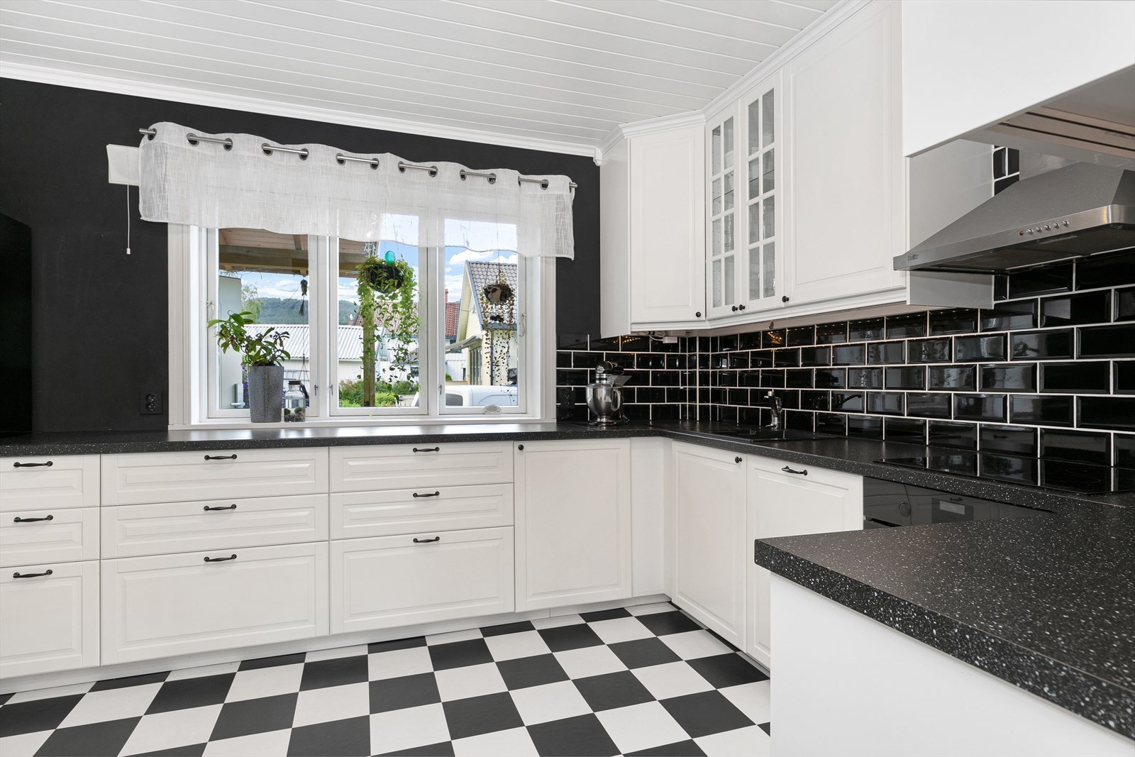 Mørk benkeplate med oppvaskkum av kompositt (svart) med sidekum og sideplate, samt svarte fliser på veggen. Integrert hvitevarer som stekeovn og oppvaskmaskin medfølger. Galleribilde