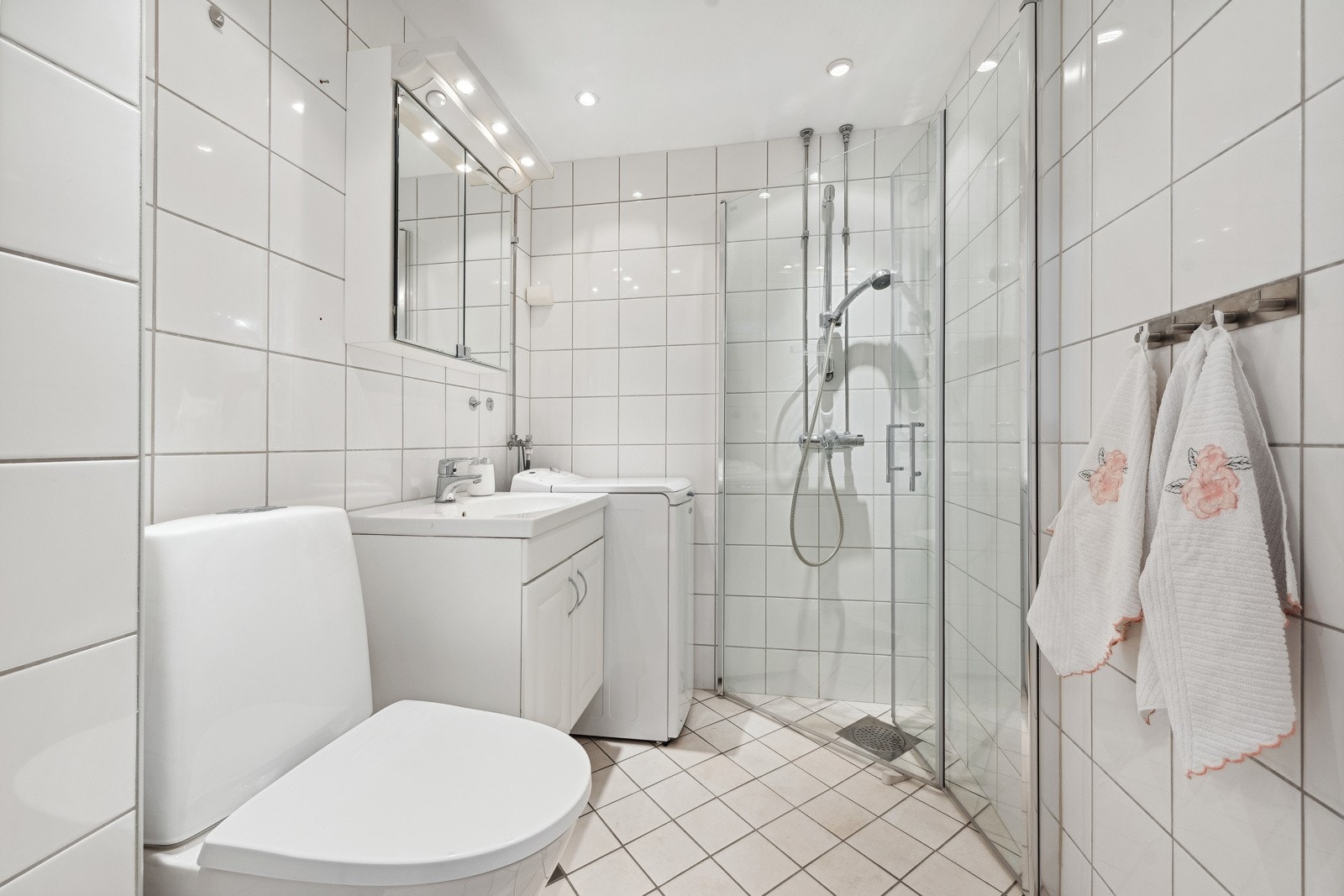 Badet er utstyrt med heldekkende servant med servantskap. Speilskap med lysarmatur, toalett, dusjhjørne og opplegg for vaskemaskin. Galleribilde