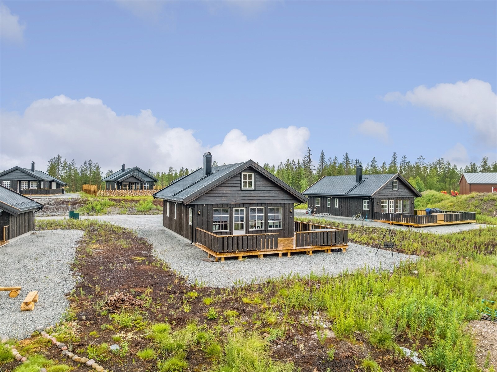 Gruset innkjørsel og gårdsplass med noe naturtomt. Galleribilde