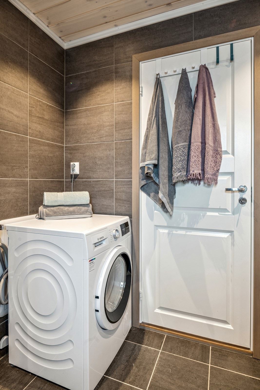 Badet er innredet med servantskap, veggmontert toalett, veggmontert dusj og opplegg for vaskemaskin. Galleribilde