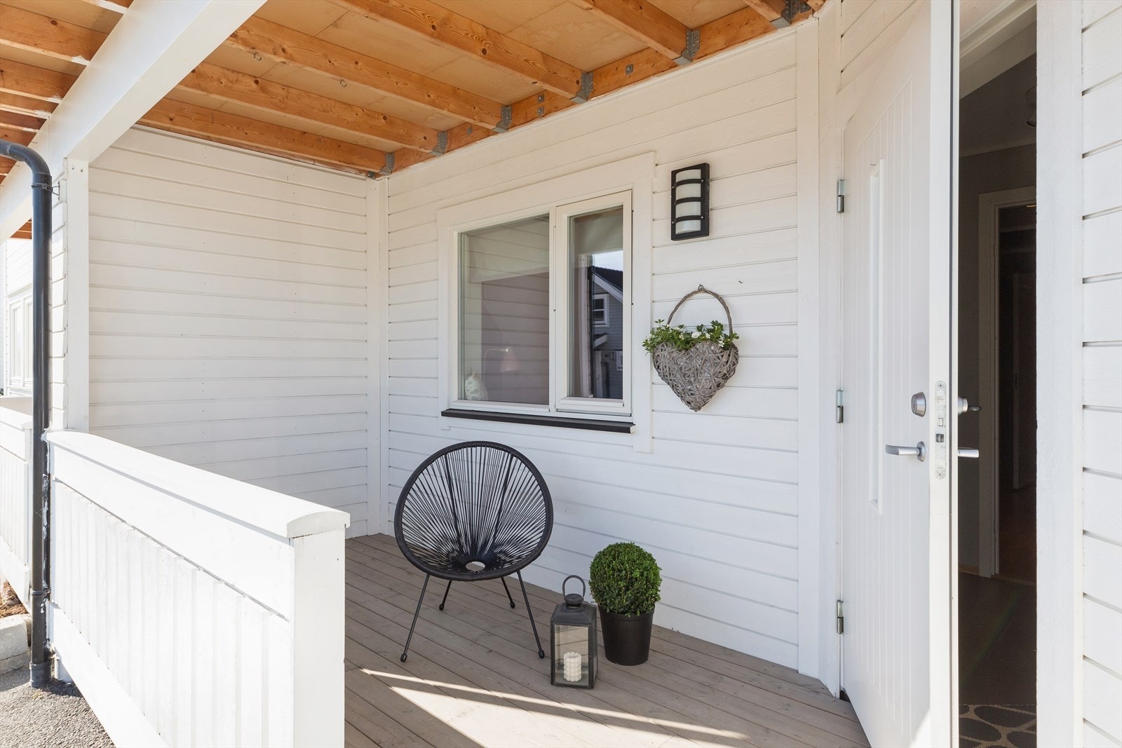 Boligen har et flott, overbygd inngangsparti med utebelysning, hvitt rekkverk og tilknyttet terrasse. Galleribilde