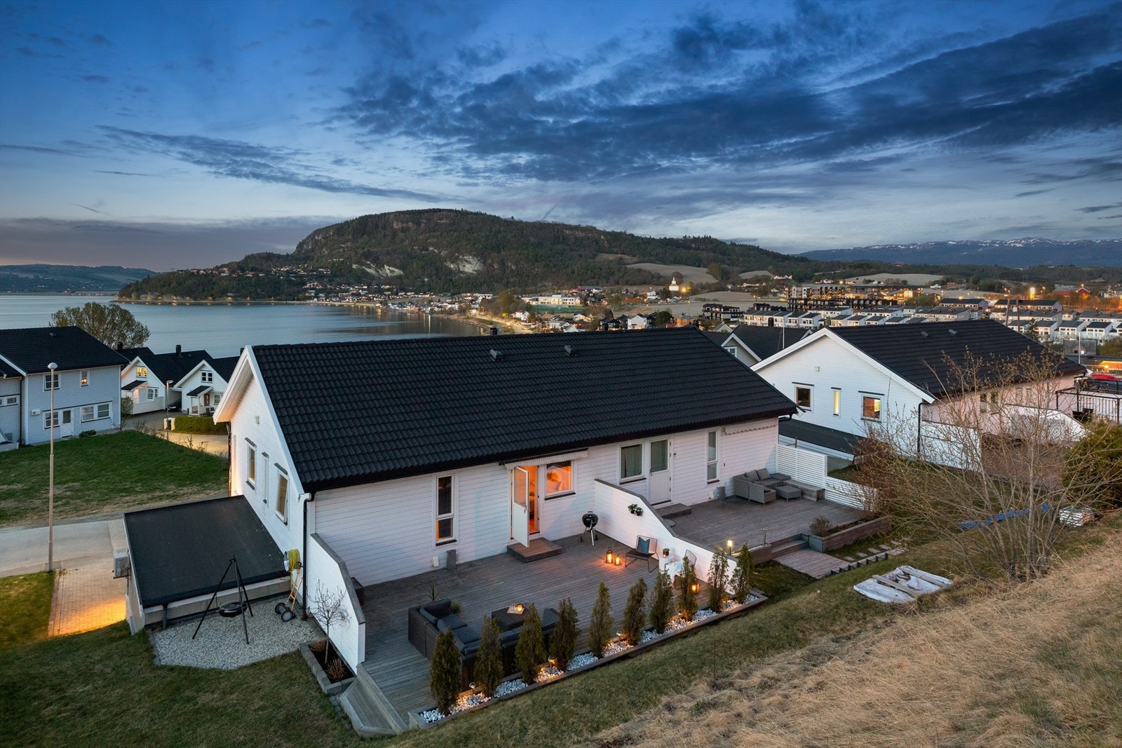 Terrassen i bakkant av boligen ligger skjermet med levegger på begge sider. Det er trapp ned til en gruset uteplass. Galleribilde