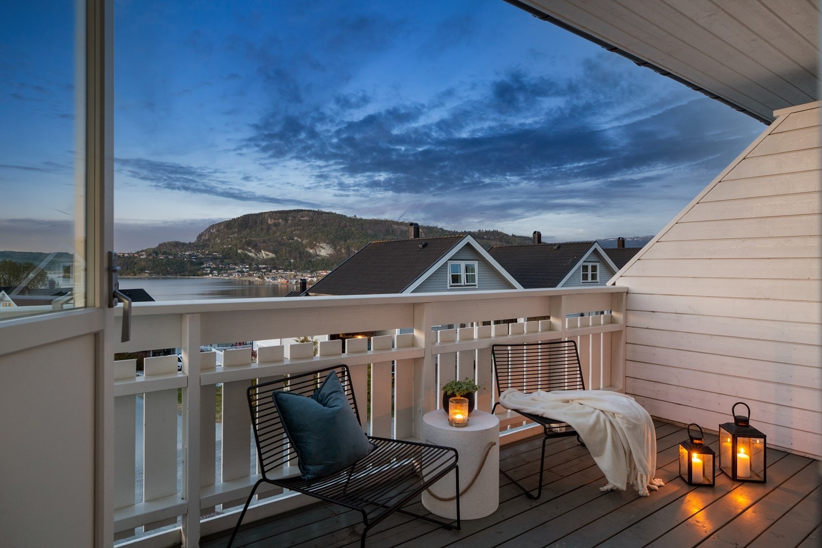 Den overbygde balkongen utenfor stue og kjøkken har levegg mot nabo og hvitmalt rekkverk. Galleribilde