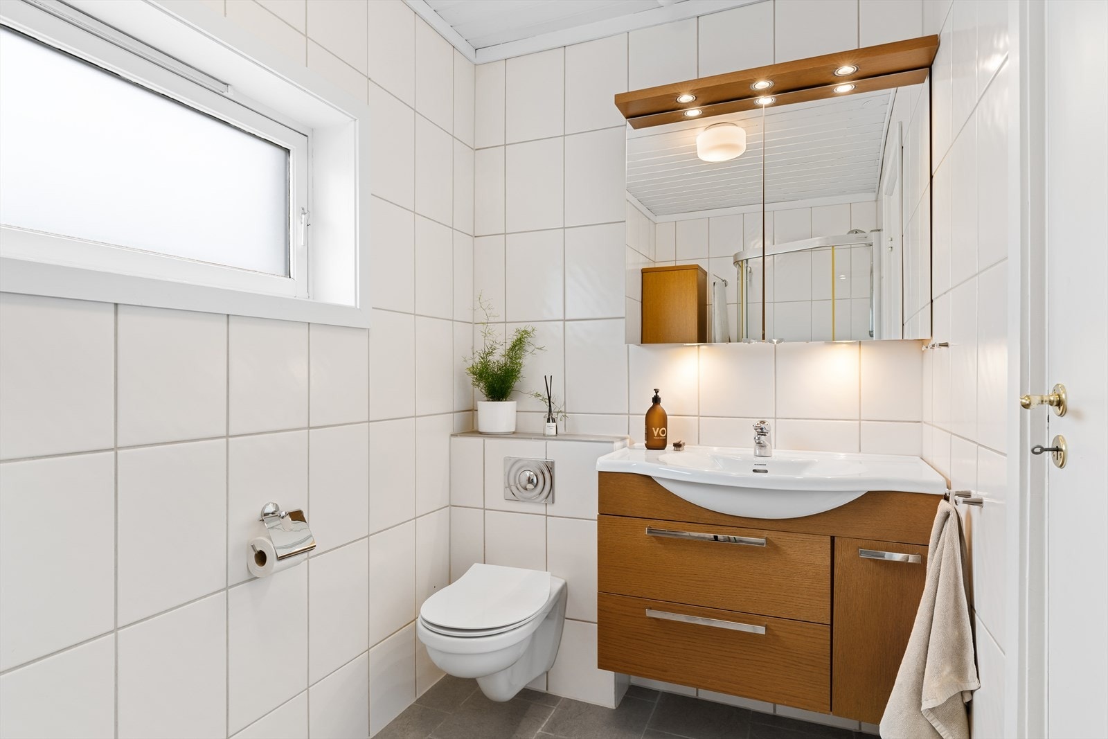 Lyst bad med vegghengt toalett og dusjsone Galleribilde