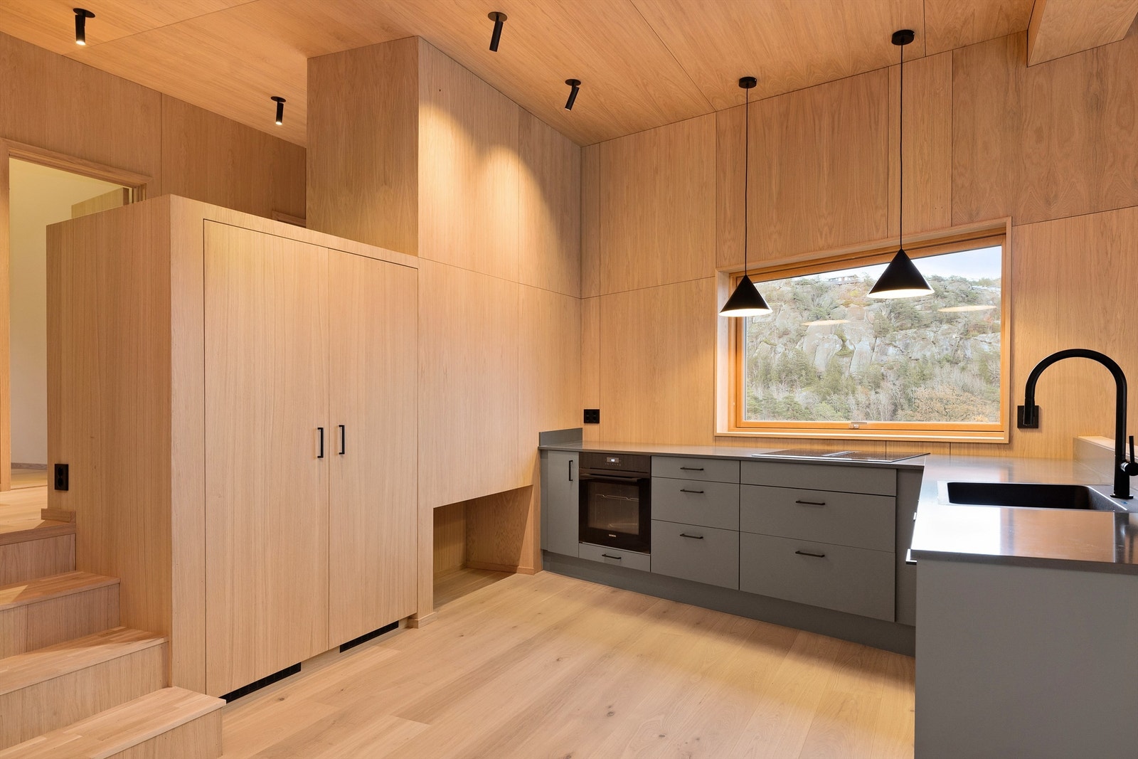 Kjøkken med nydelig benkeplate i stein. Skapdørene skjuler fryseskap og kjøleskap i full høyde Galleribilde