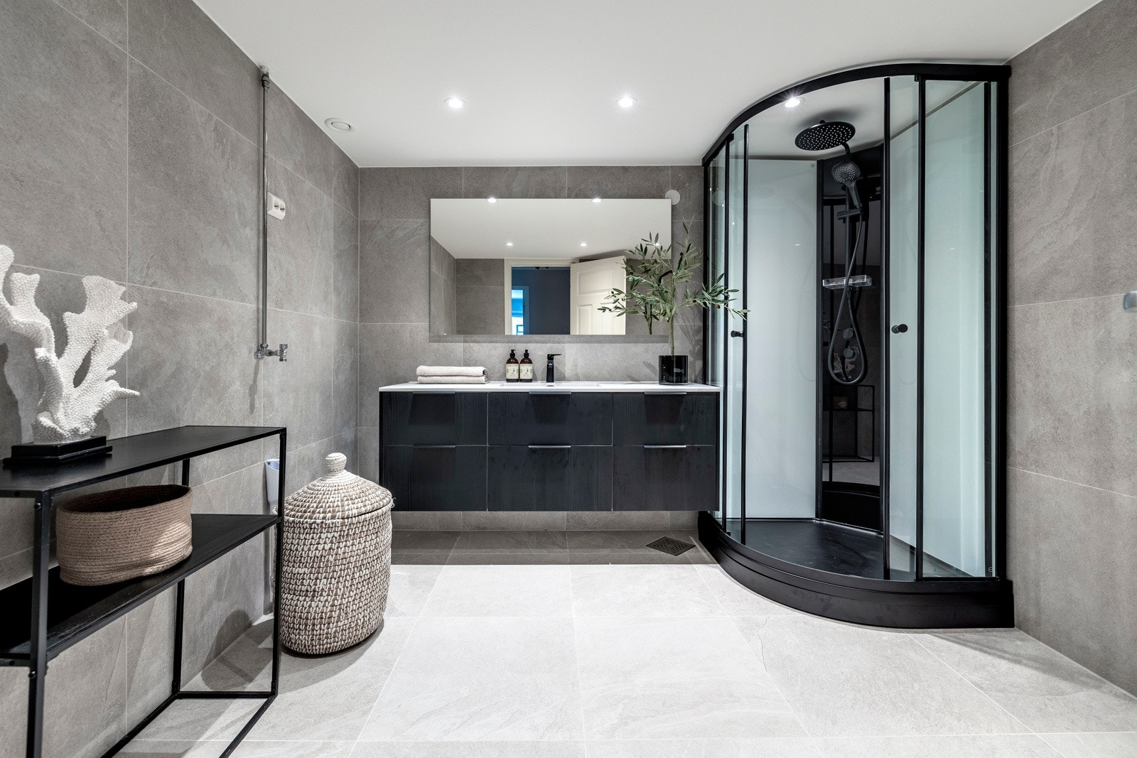 Badet ble pent pusset opp i 2024 med flis-på-flis. Her er alle overflater, innredninger, downlights og utstyr nytt. Rommet har grå storformatfliser på gulv og vegger, varme i gulvet og opplegg for vaskemaskin. Galleribilde