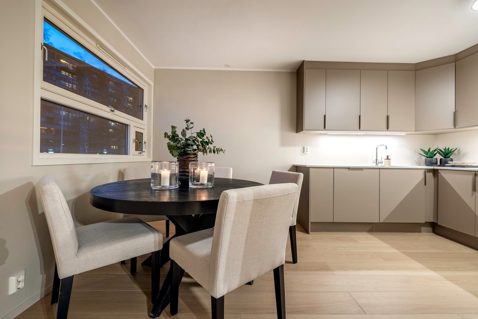 Kjøkkenet har grå, glatte fronter med stålgrep, takoppforede overskap, underlimt vaskekum og god benkebelysning. Integrert i innredningen er det induksjonstopp, stekeovn, kjøl/frys, oppvaskmaskin og ventilator. Galleribilde