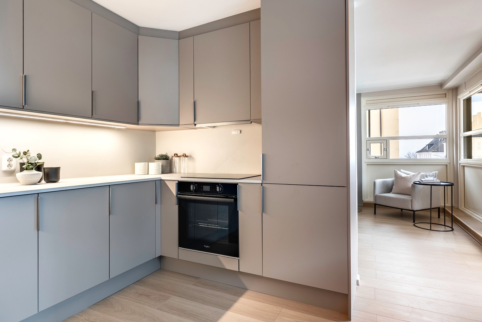 Rommet har god plass til spisebord ved vinduene, og det er god kontakt med stuen via en bred åpning. Innredningen er plassert i U-form, og har god arbeidsflyt langs benkeplater i tynn, lys kompaktlaminat. Galleribilde