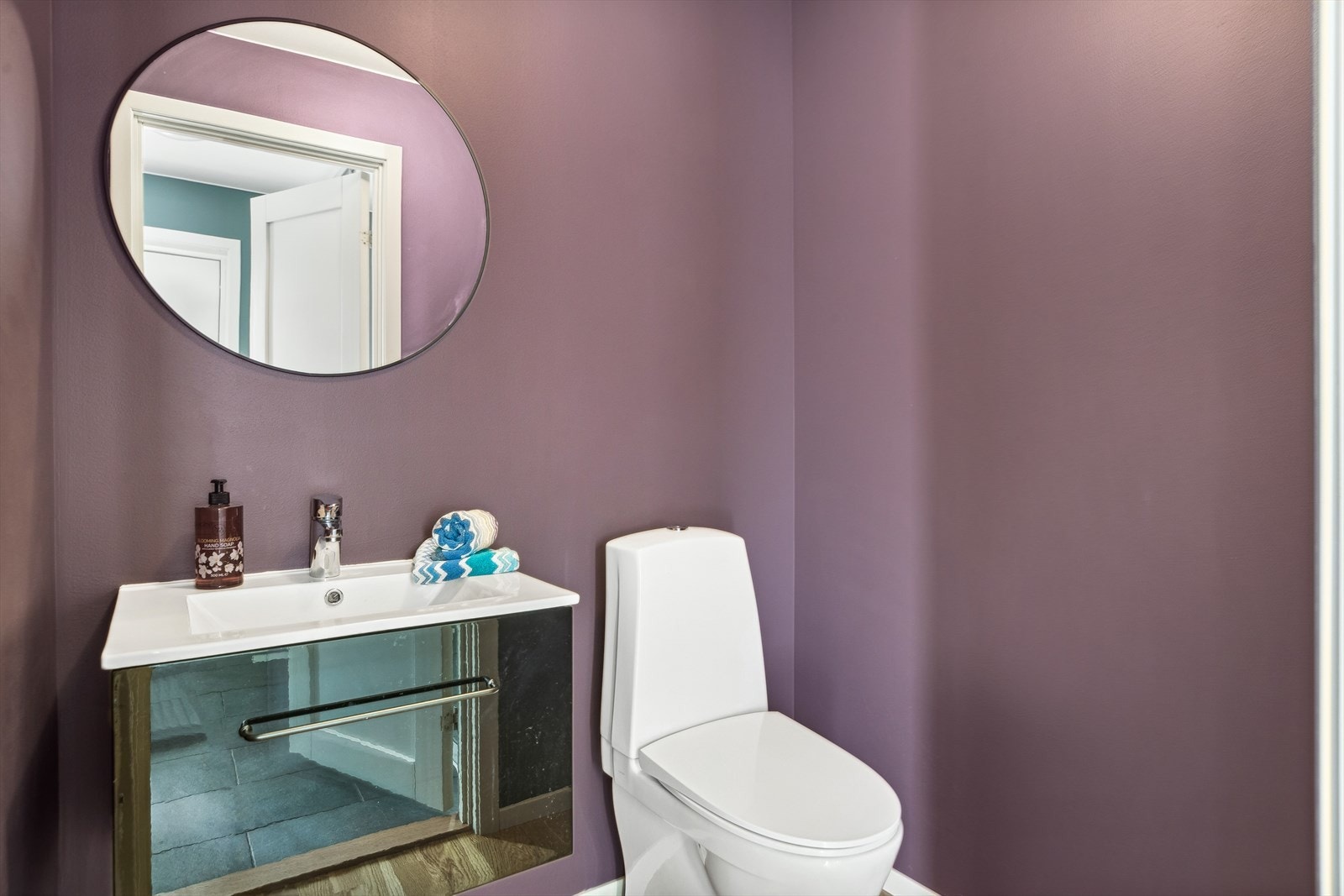 Toalettrommet har parkettgulv, plommefargede vegger, toalett og høyglanset servantinnredning. Galleribilde