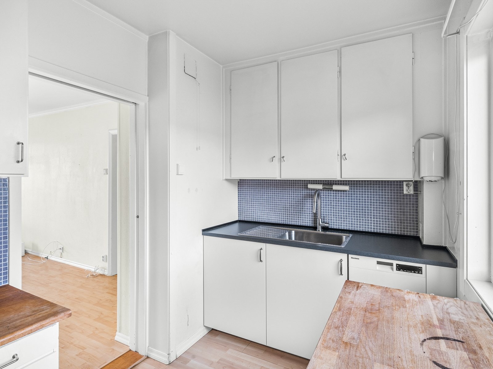 Kjøkkeninnredning på vegg mot bad/wc med slette fabrikklakkerte fronter, laminat benkeplate med fliser over, enkel oppvaskkum og opplegg for oppvaskmaskin
fra 2021, ellers original kjøkkeninnredning Galleribilde