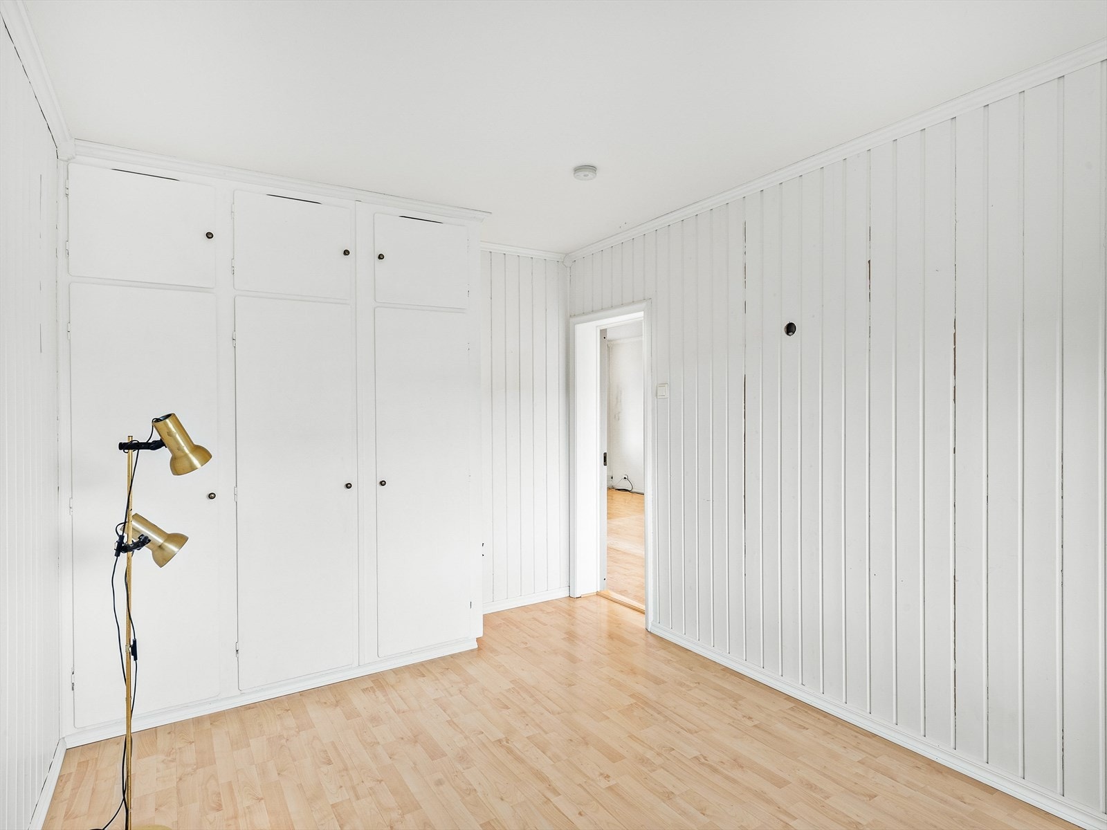 Soverom 1 med laminat på gulv, malt panel og malte strier på vegger samt malt tak. Det er montert originalt plassbygd garderobeskap. Galleribilde